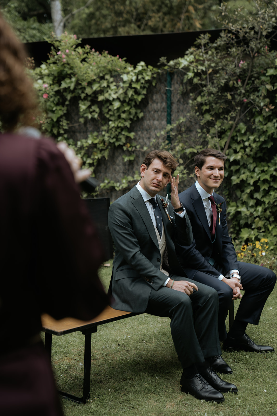 Bride and groom kissing on steps with bride holding bouquet as guests throw confetti and take photos.