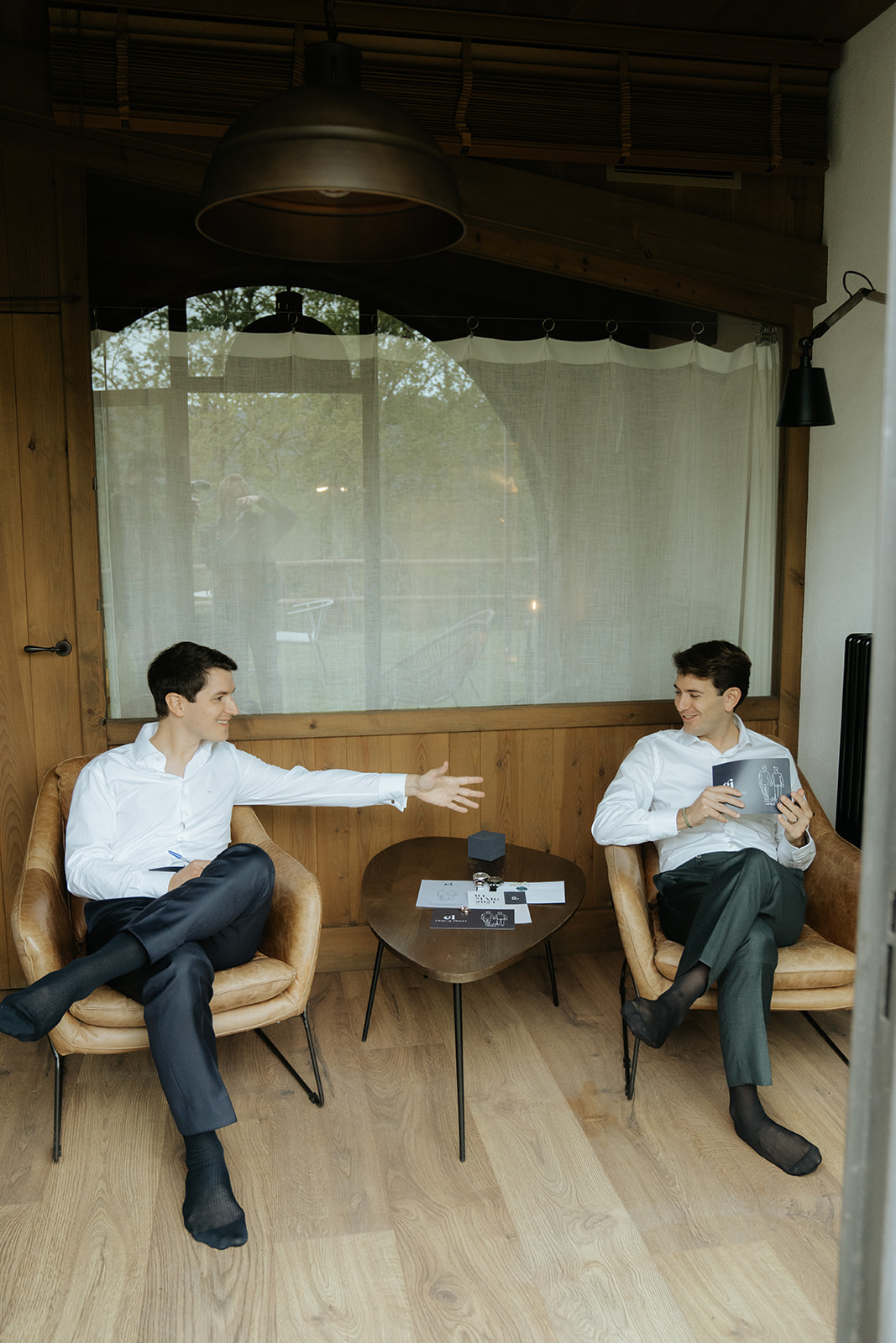 Woman in silky white robe sitting on a brown couch holding a bouquet of white roses.