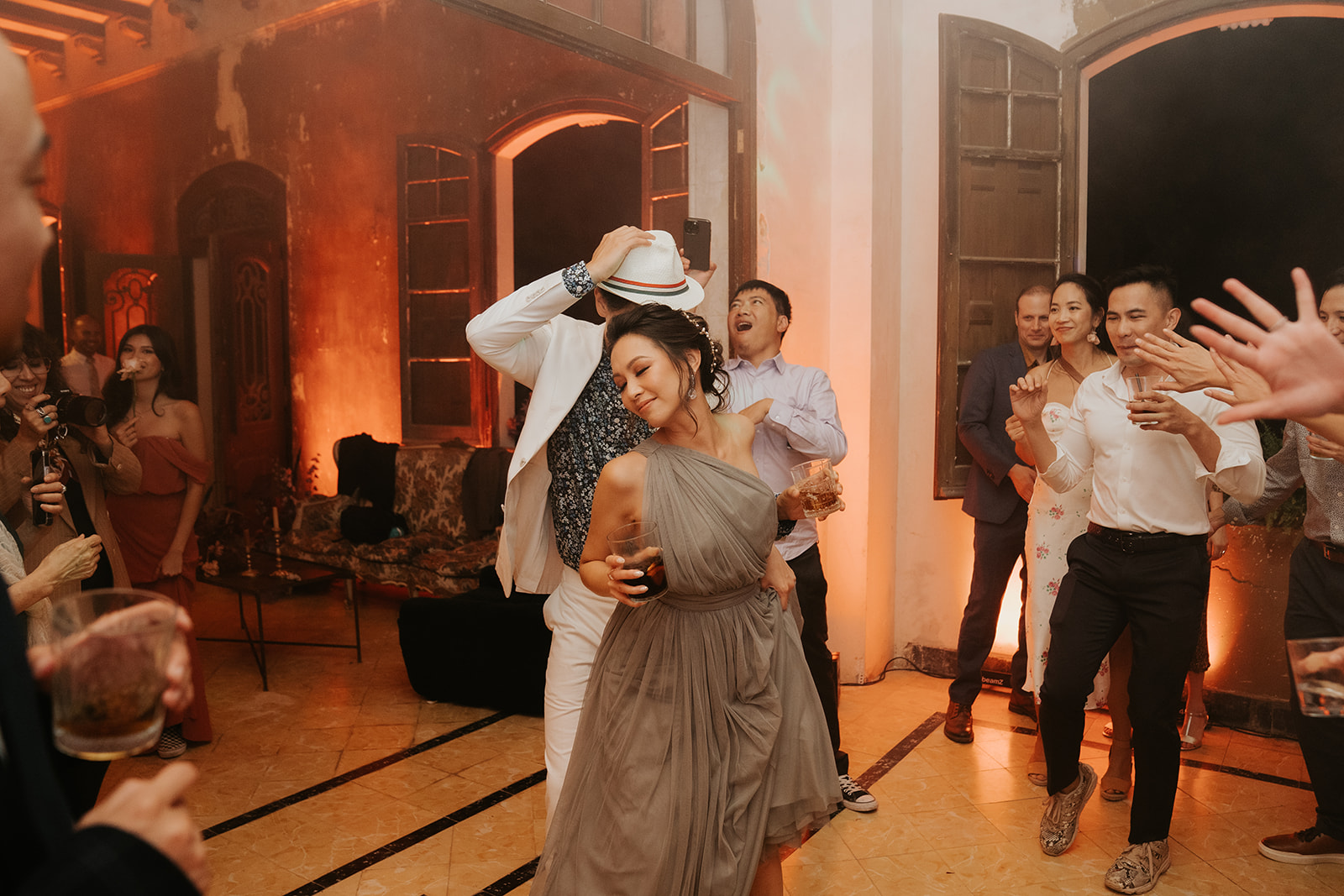 Black and white photo of a man adjusting his formal shirt and bow tie while looking at his reflection in an oval mirror.