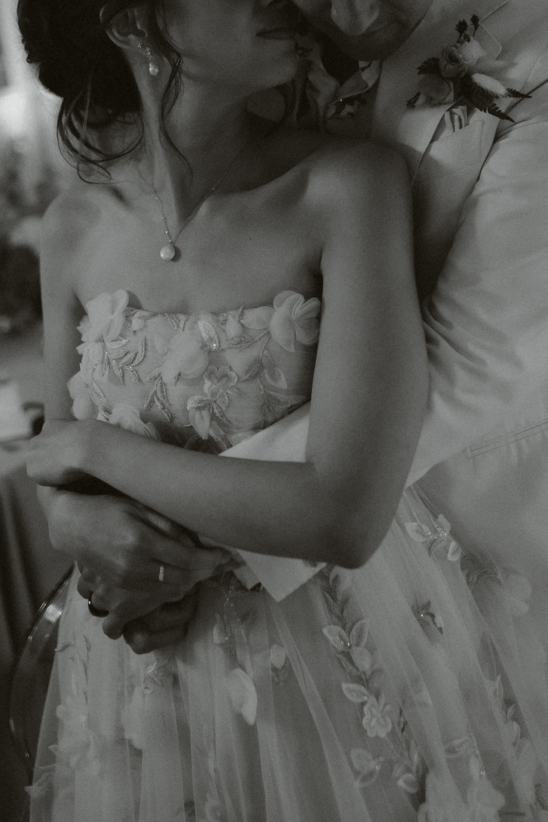 Bride and groom holding hands during wedding ceremony, bride wearing lace dress and groom in dark suit.
