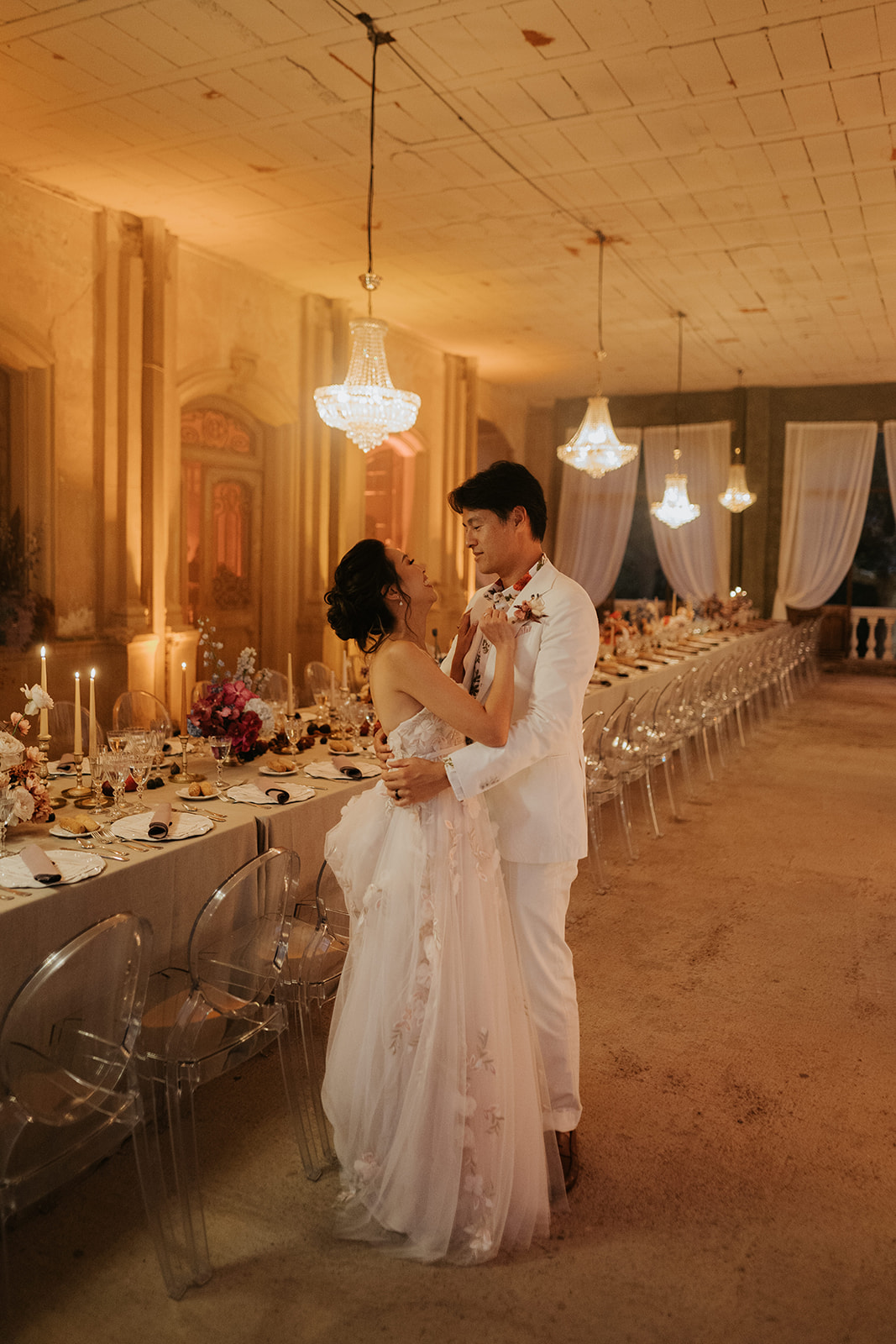 Black and white photo of a couple embracing during a dance in a dimly lit venue with a bright light above.