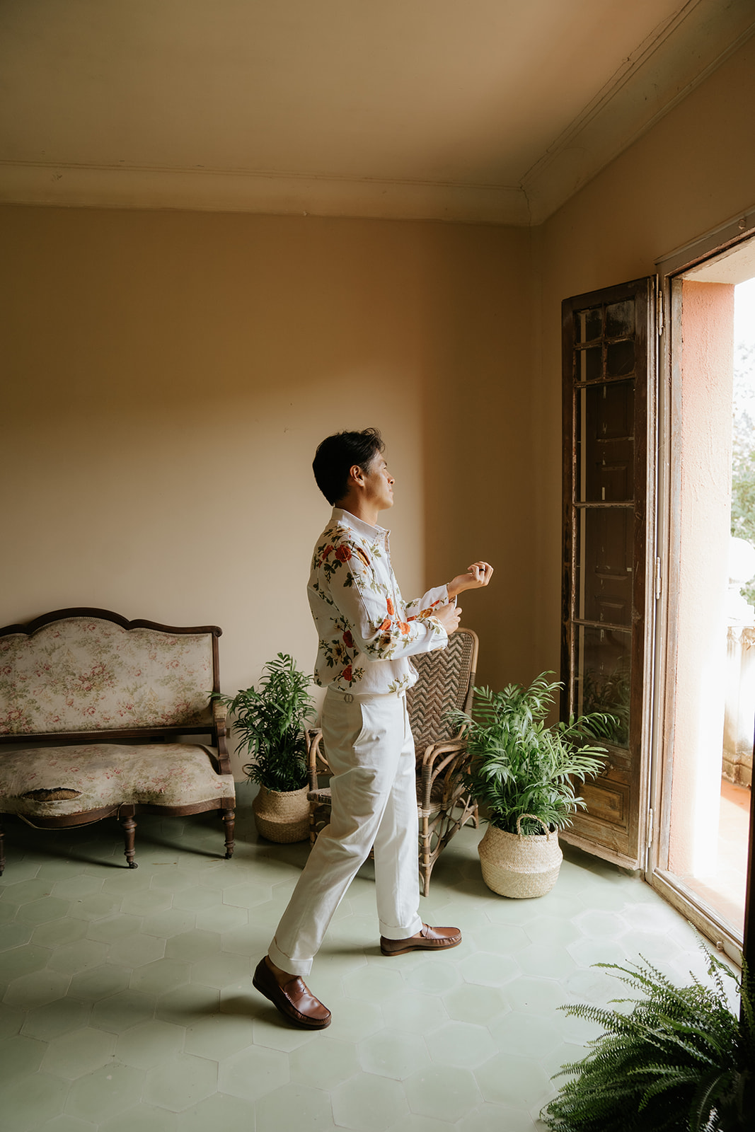 Person holding a gold engagement ring above a black ring box, wearing a white shirt and black pants.
