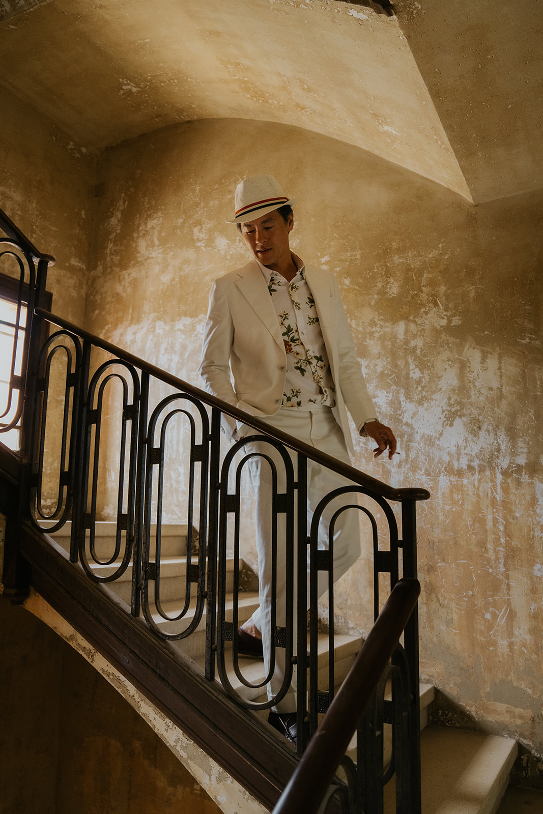 Four women in satin robes smiling and holding hands in an ornately decorated room with a wedding dress hanging in the background.
