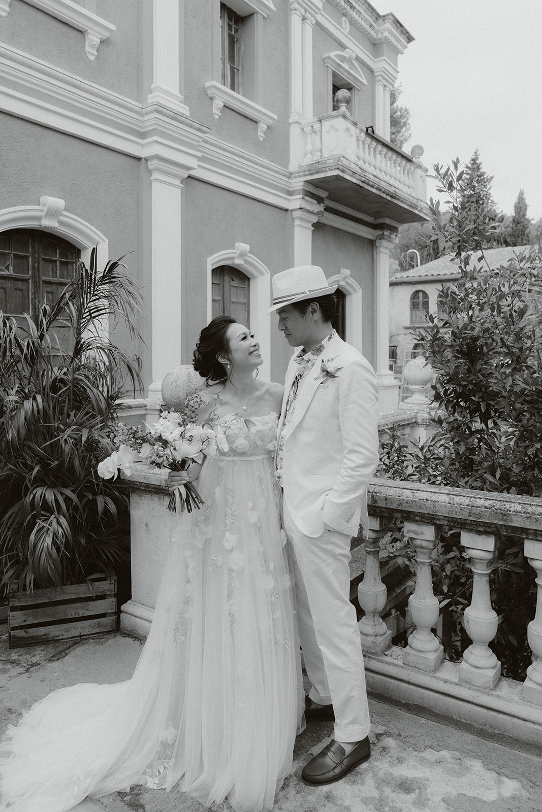 Bride and groom standing before a priest in a grand church with ornate golden altar and stained glass windows during a wedding ceremony.