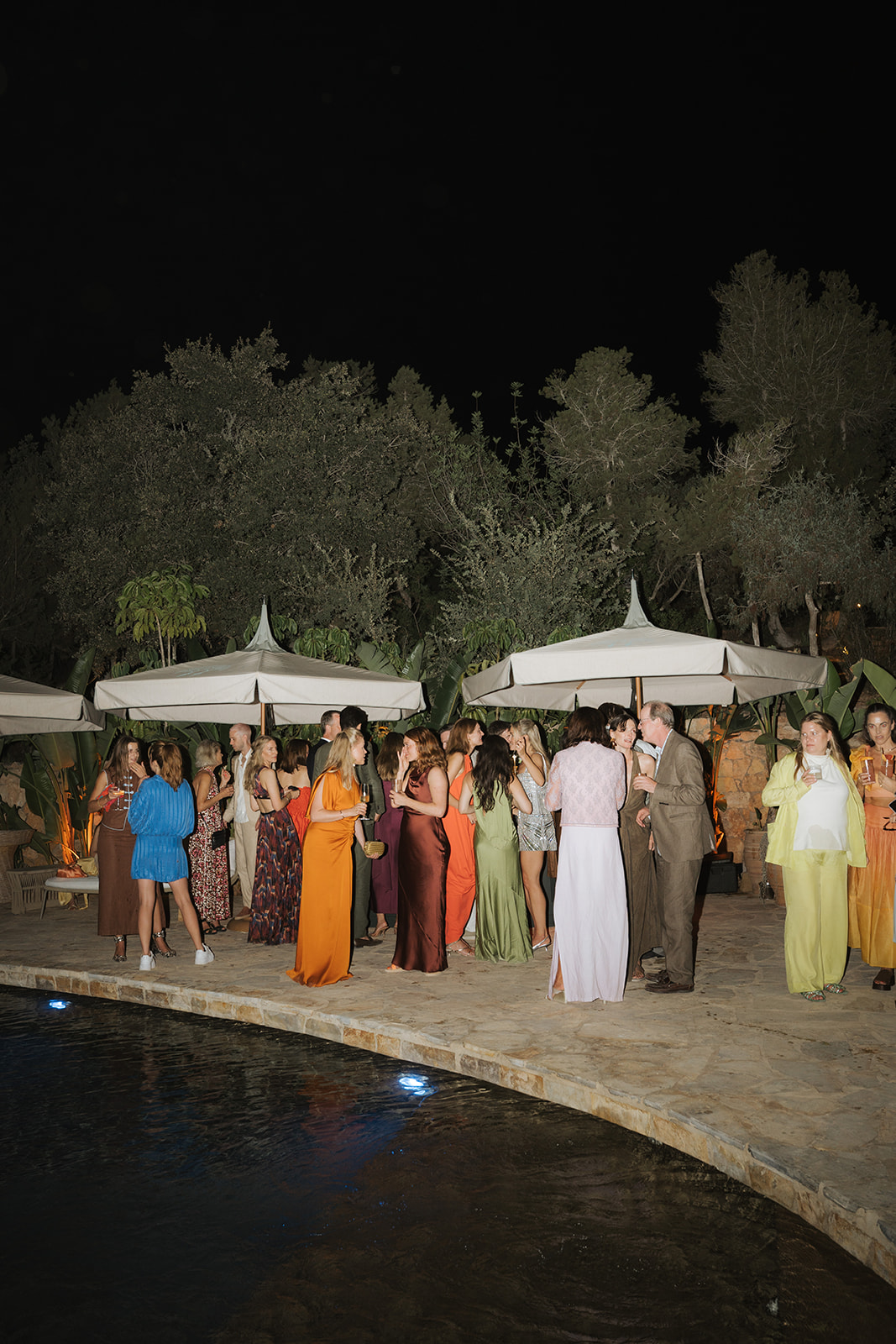 Three women in elegant dresses inside a decorated room with a chandelier, viewed through partially open doors.