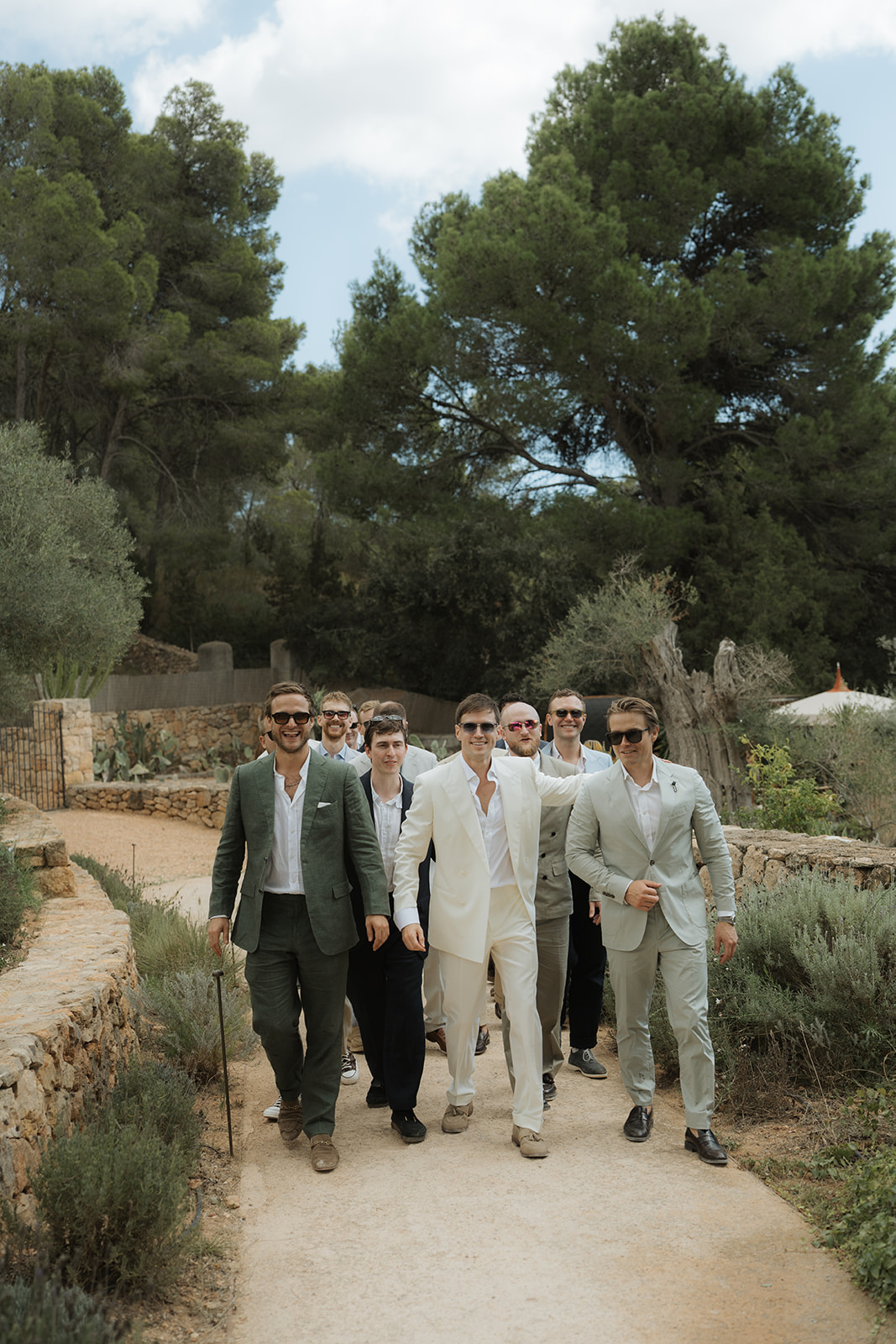 Elegant white off-shoulder wedding dress hanging on ornate cream and gold wardrobe with matching heels and veil on nearby chair.