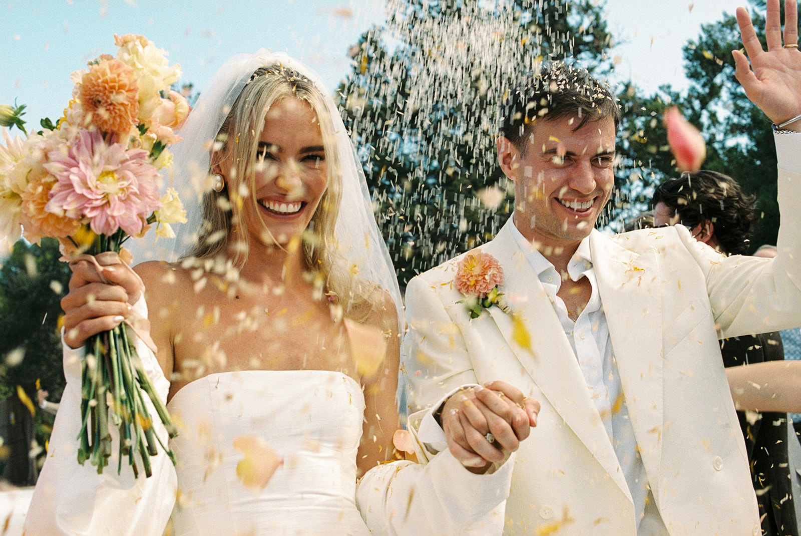 Black and white photo of a man adjusting his formal shirt and bow tie while looking at his reflection in an oval mirror.