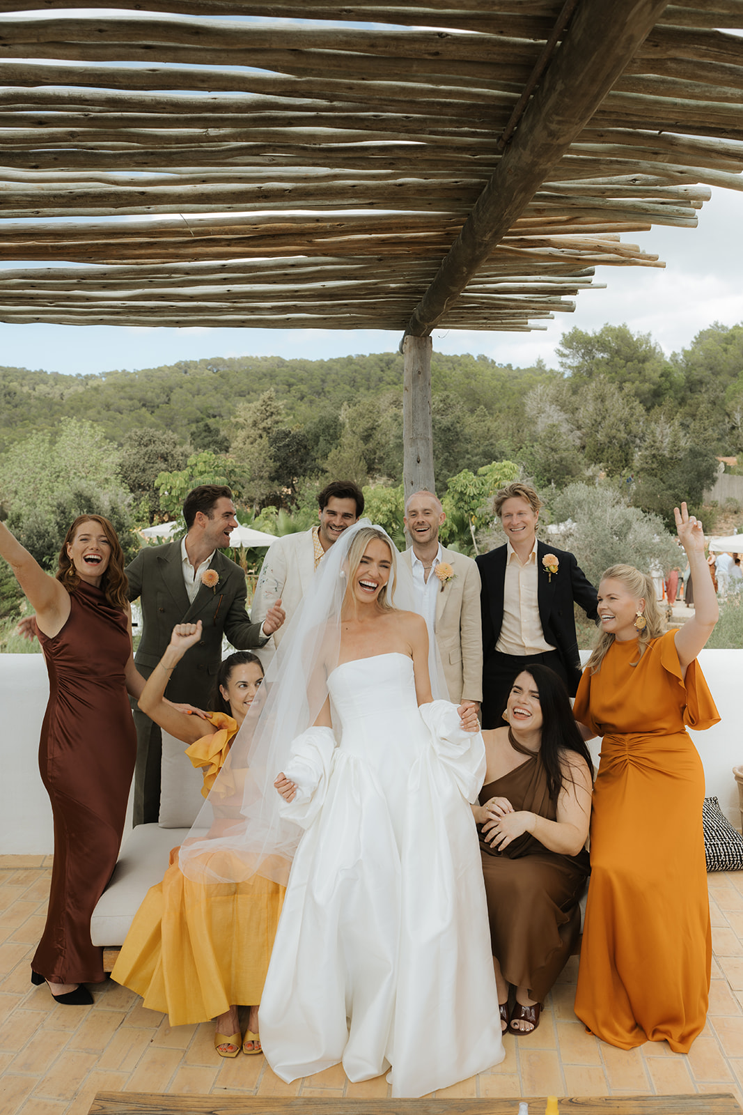 Bride and groom kissing on steps with bride holding bouquet as guests throw confetti and take photos.
