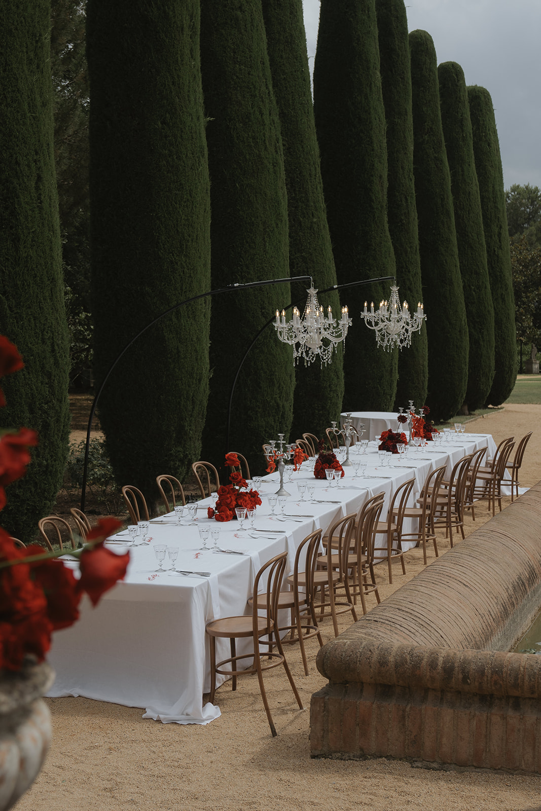 Elegant white off-shoulder wedding dress hanging on ornate cream and gold wardrobe with matching heels and veil on nearby chair.