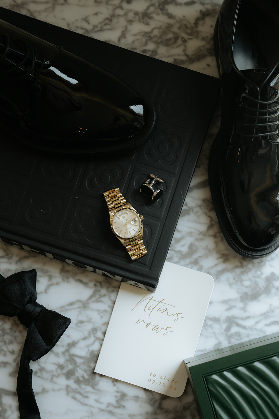Person holding a gold engagement ring above a black ring box, wearing a white shirt and black pants.
