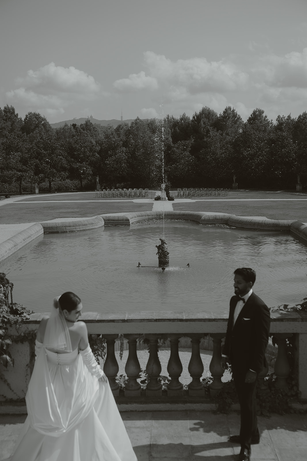 Bride and groom kissing on steps with bride holding bouquet as guests throw confetti and take photos.