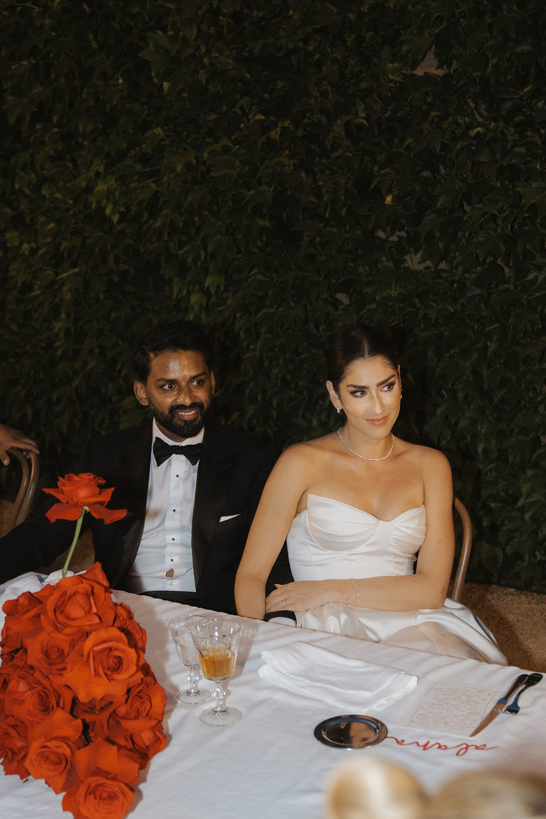 Bride and groom holding hands during wedding ceremony, bride wearing lace dress and groom in dark suit.
