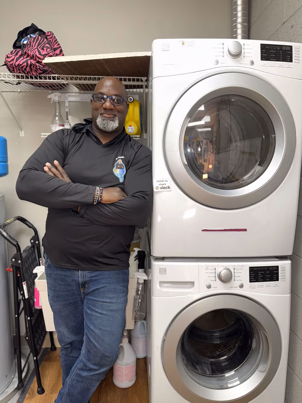 The owner of Pollard's Dryer Vent Cleaning service stood next to a washer and dryer.