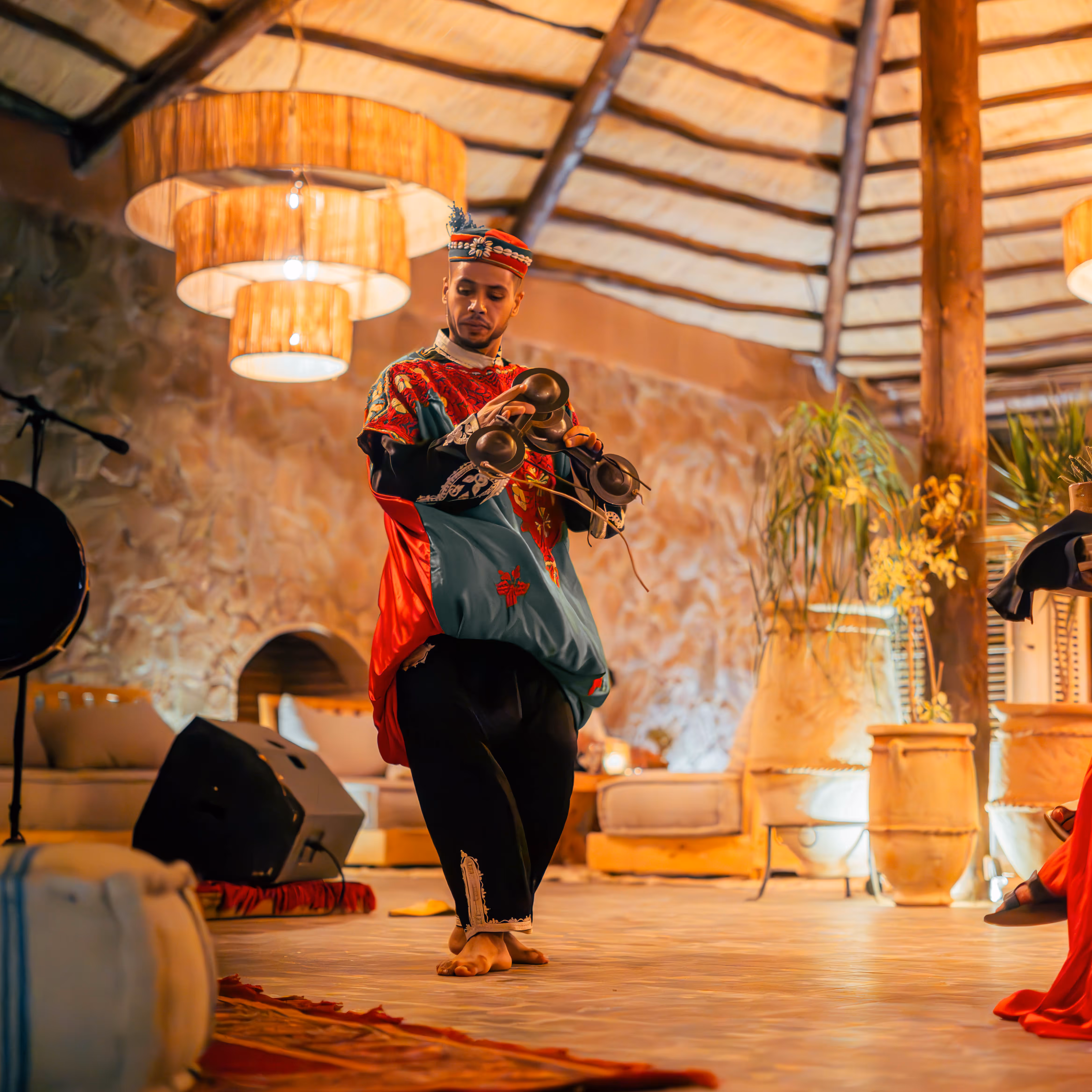 Evening view of a vibrant market with colorful stalls and crowds in a desert city surrounded by adobe buildings under a clear sky.