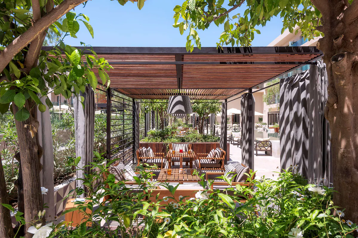 Rolling barren hills with mountains in the background under a clear pastel sky at sunset.