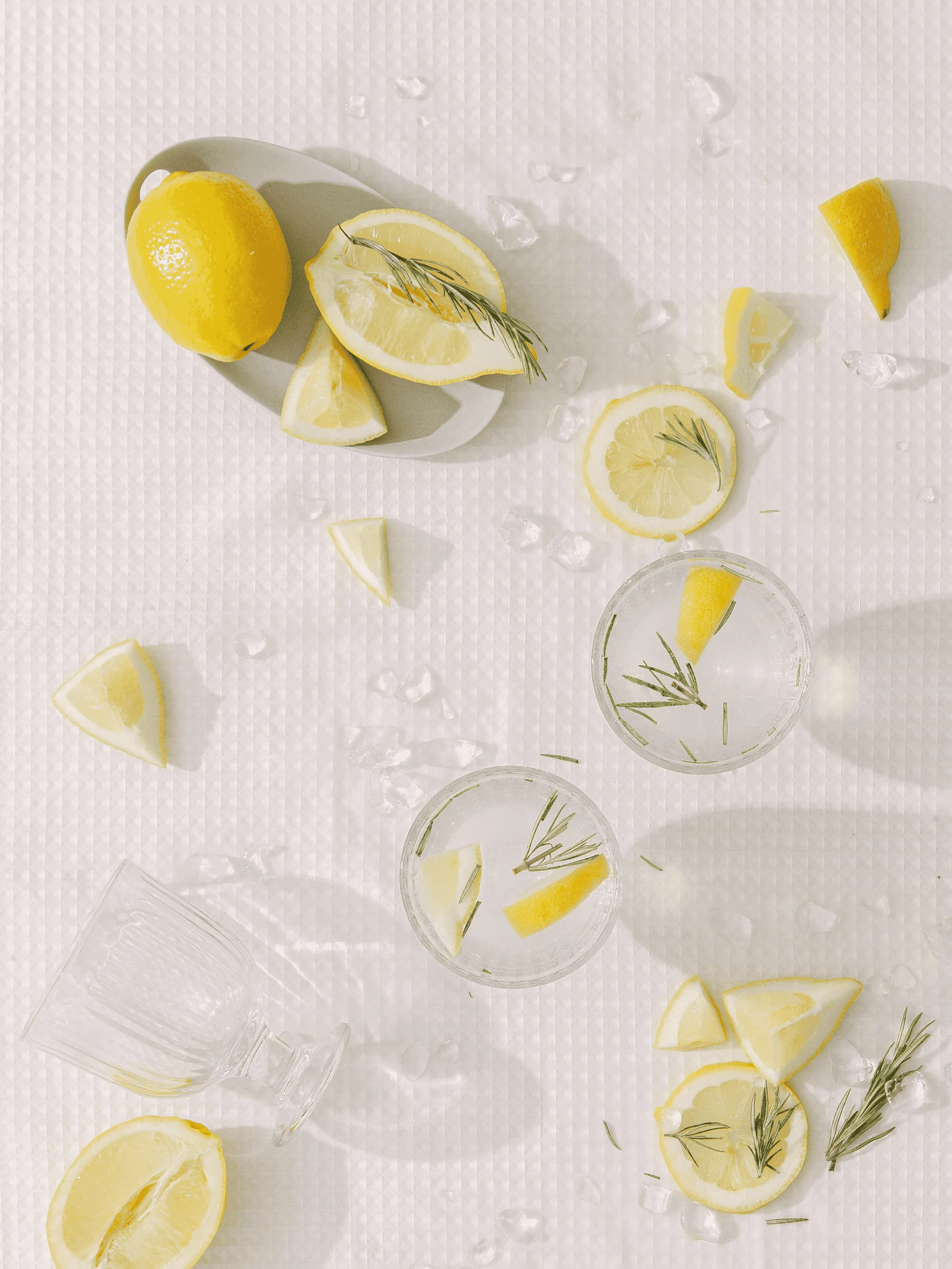 lemons in a bowl and some pieces cut and placed in cups on a table cloth