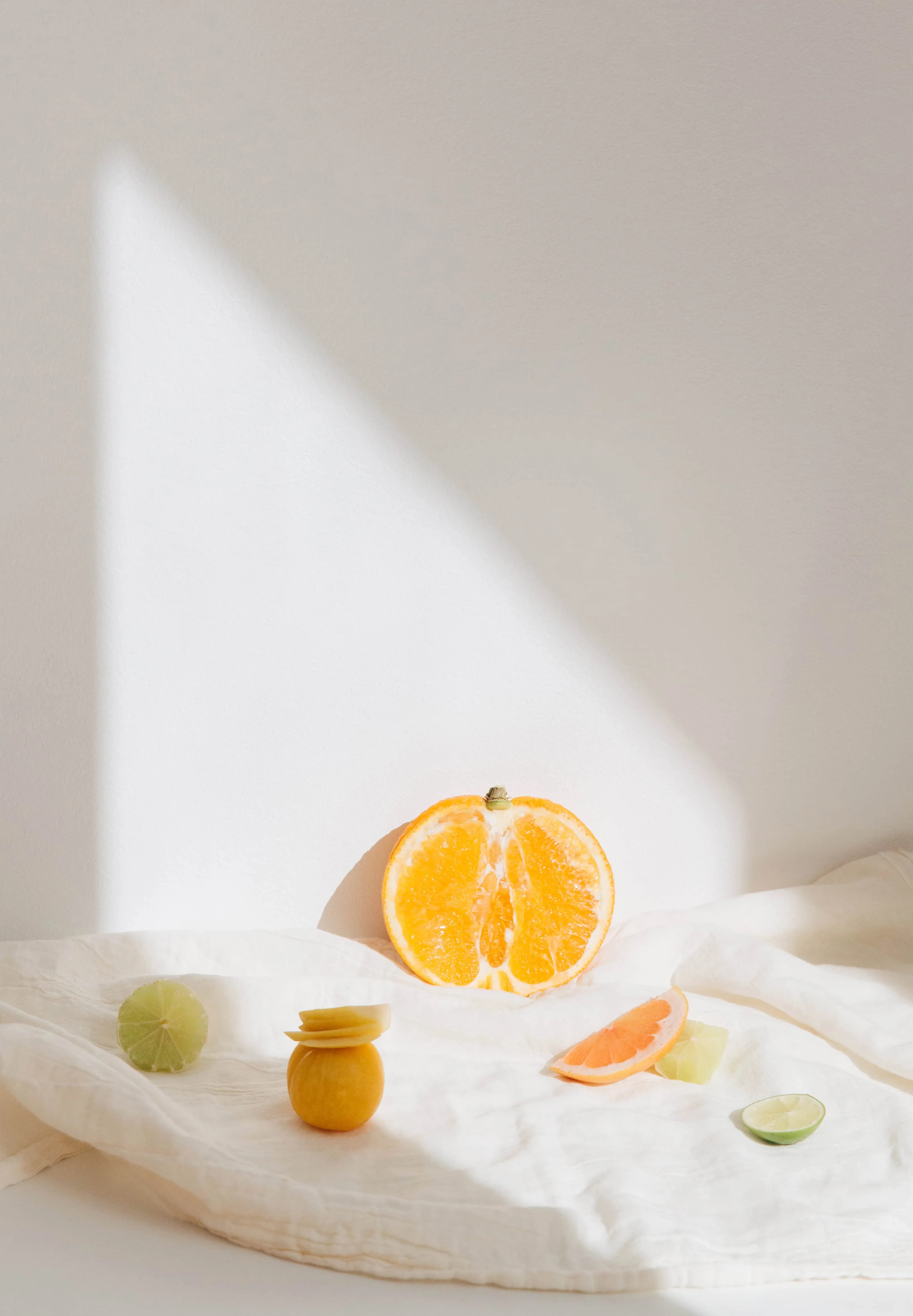 fruit laid out in a minimalistic white background with sunlight reflecting on some of the fruits