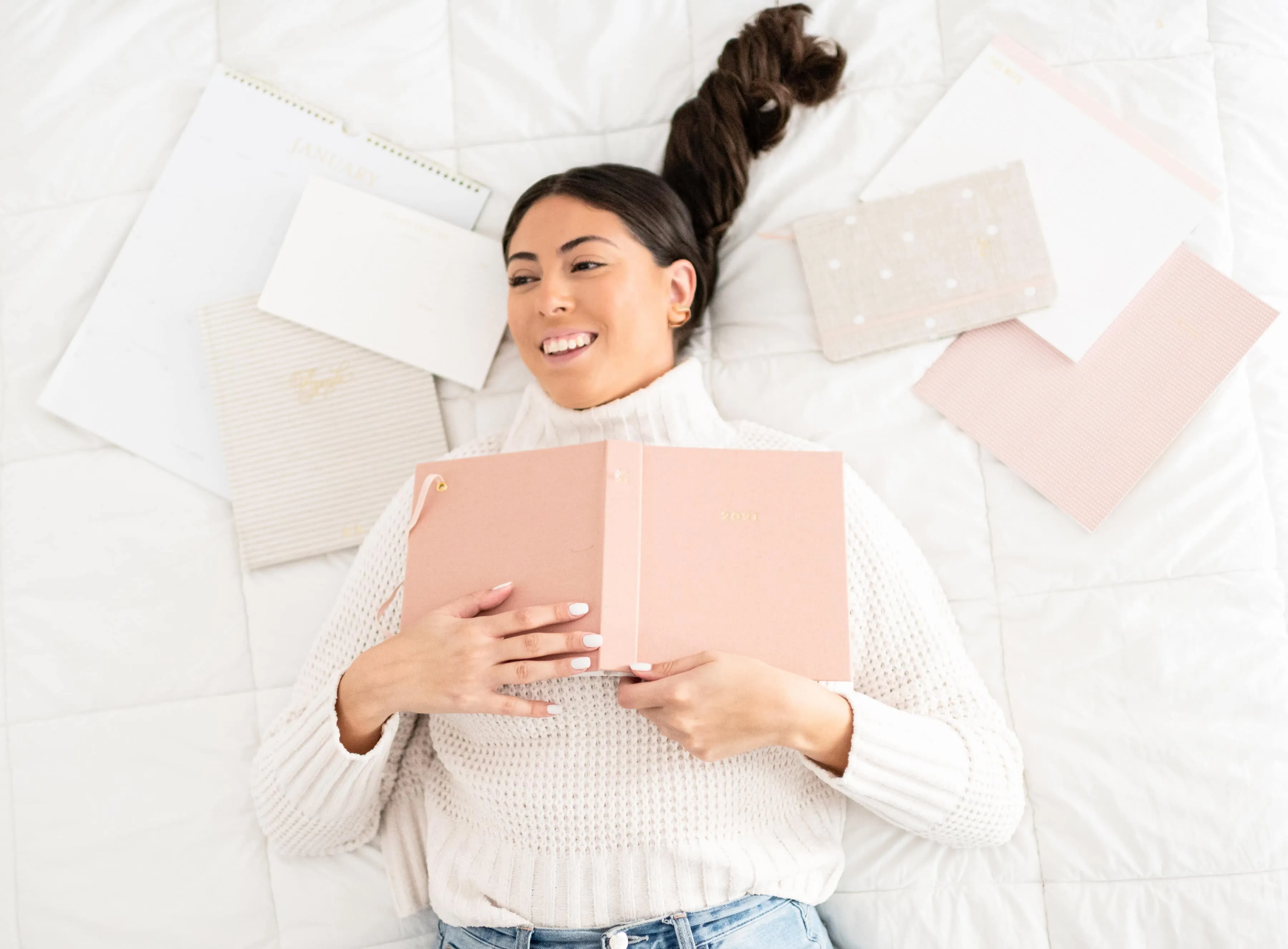 woman lying down holding a notebook
