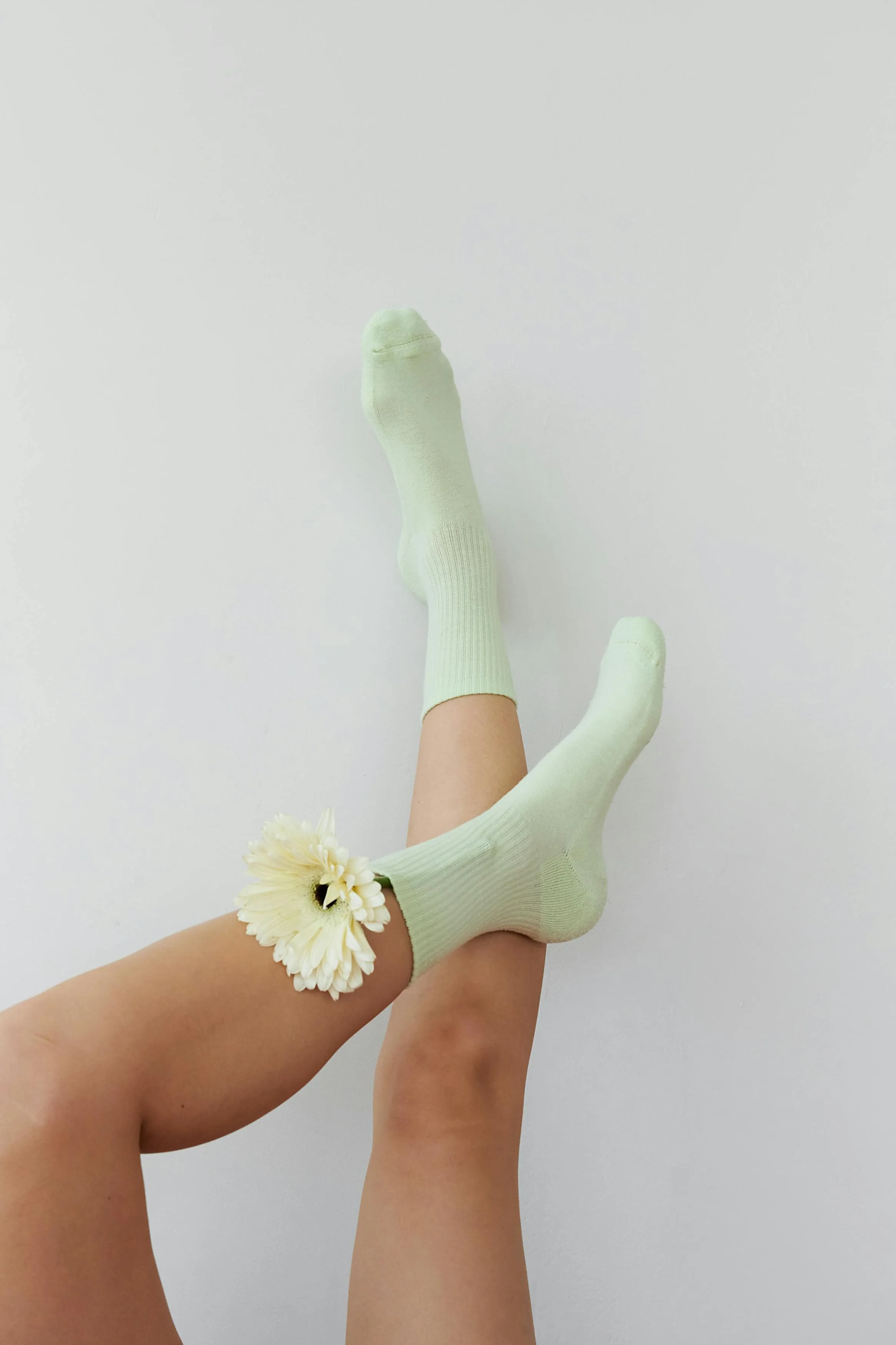 someone's feet laid against the wall wearing socks with a flower in one of the socks