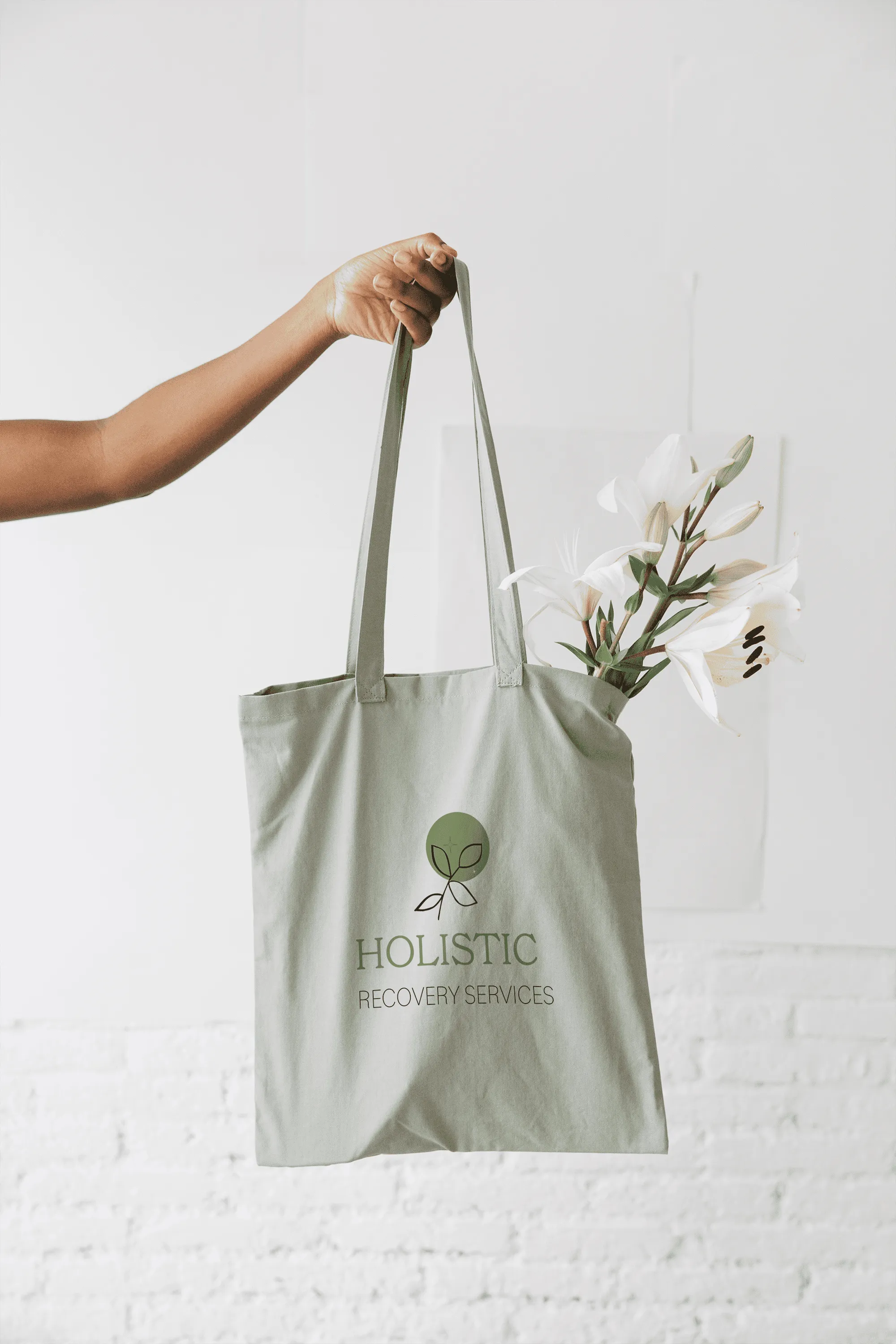 someone holding a carry bag embedded with a logo designed for a  therapist. logo says 'holistic recovery services'