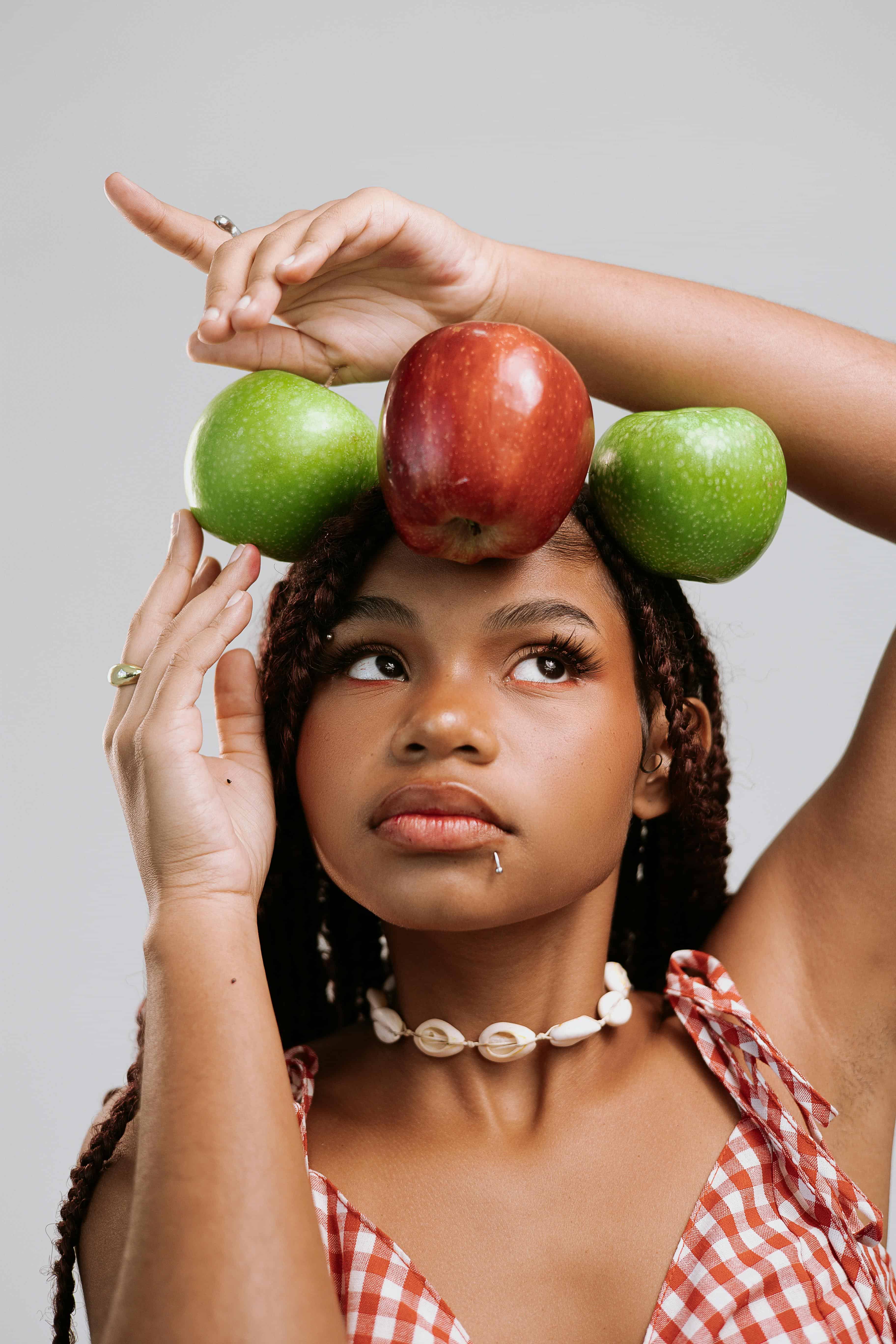 woman holding apples around her head