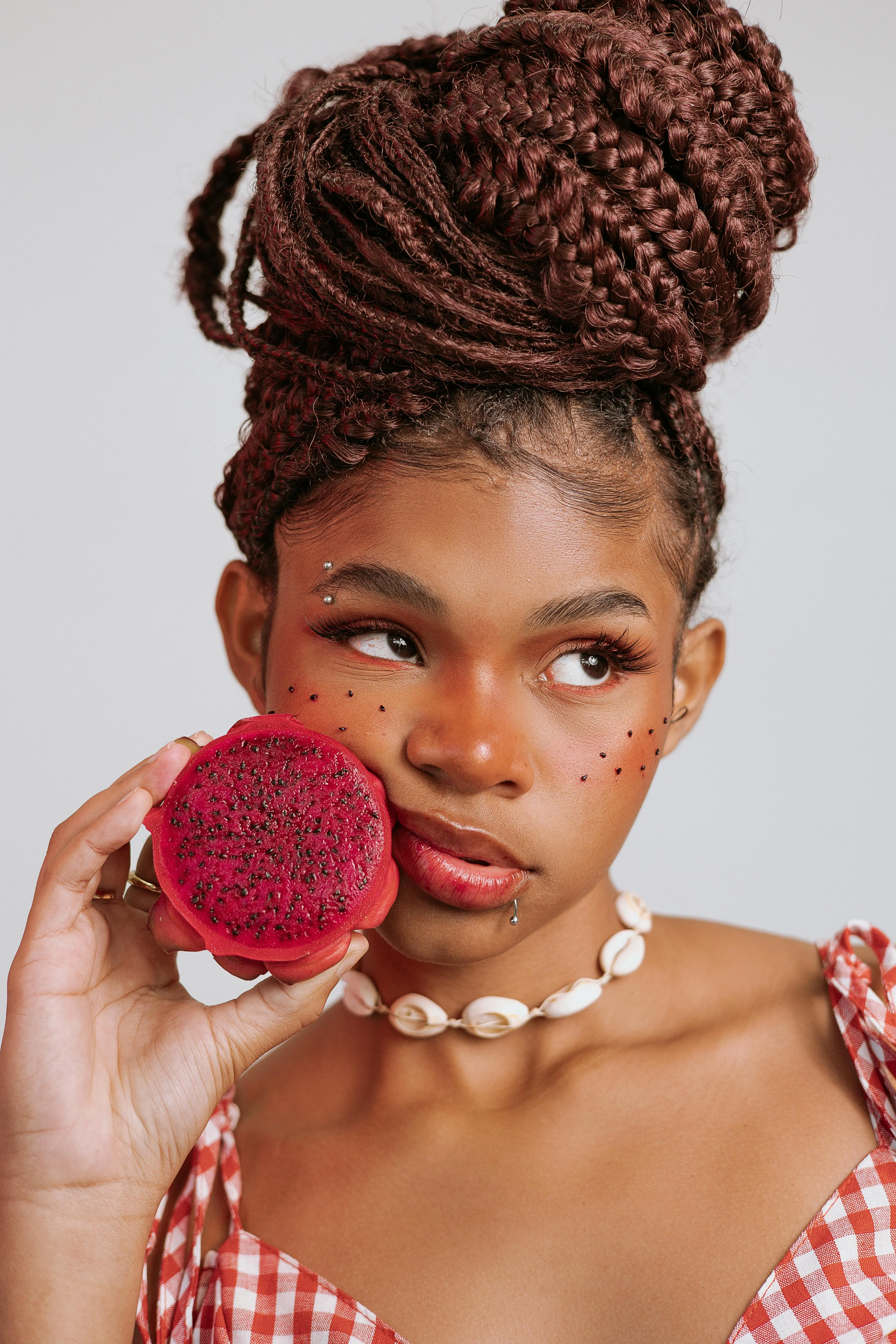 woman holding a fruit close to her face and looking rebellious