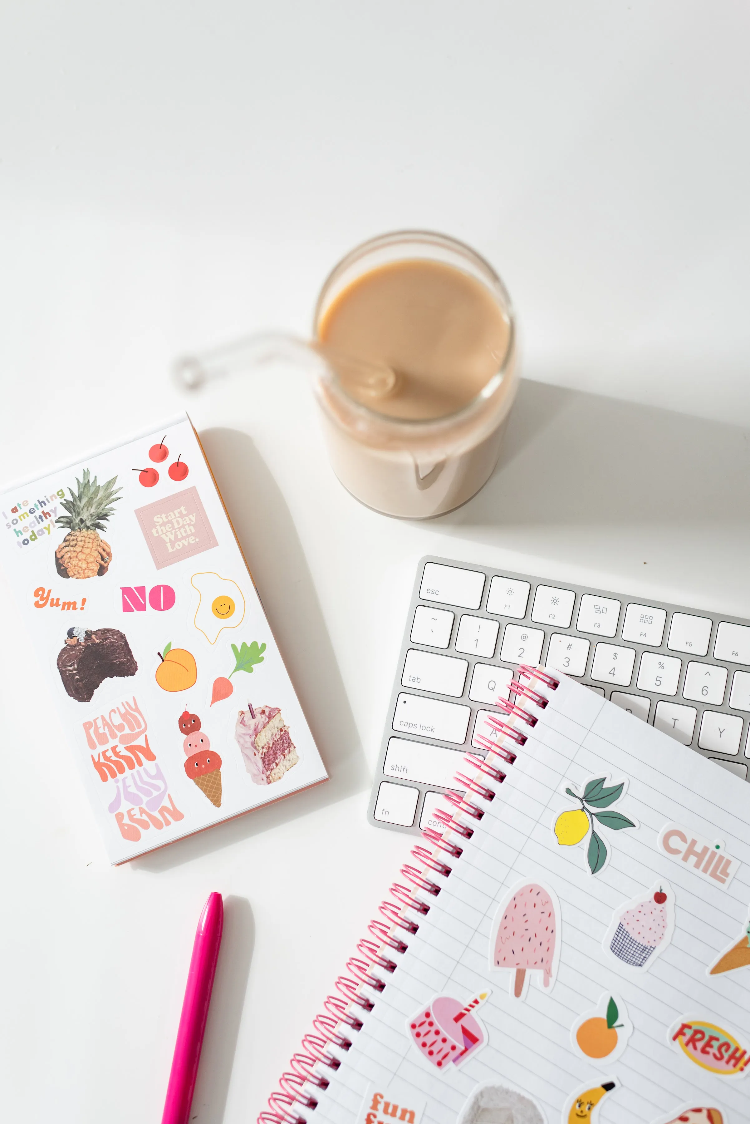 notebooks, cup of tea or coffee, keyboard and pen laid out on a flat surface