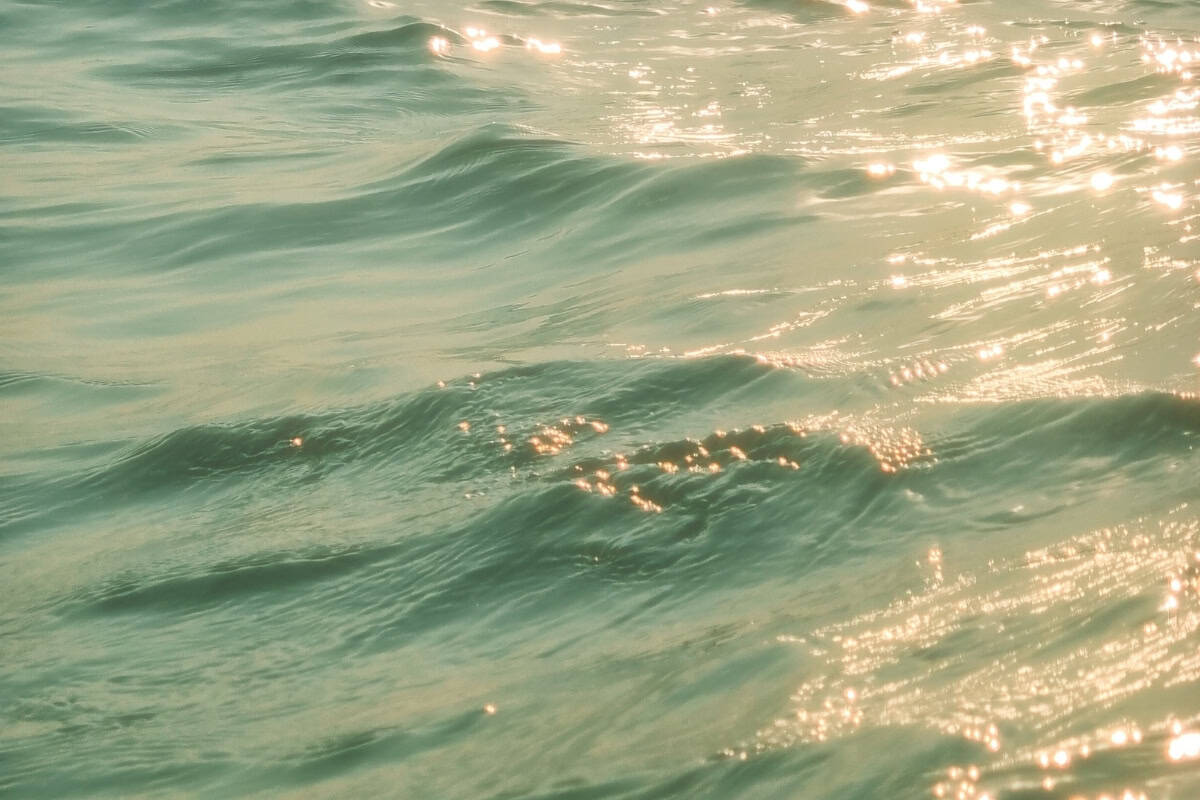Sunlight sparkling on soft ocean waves with gentle ripples on the water surface.