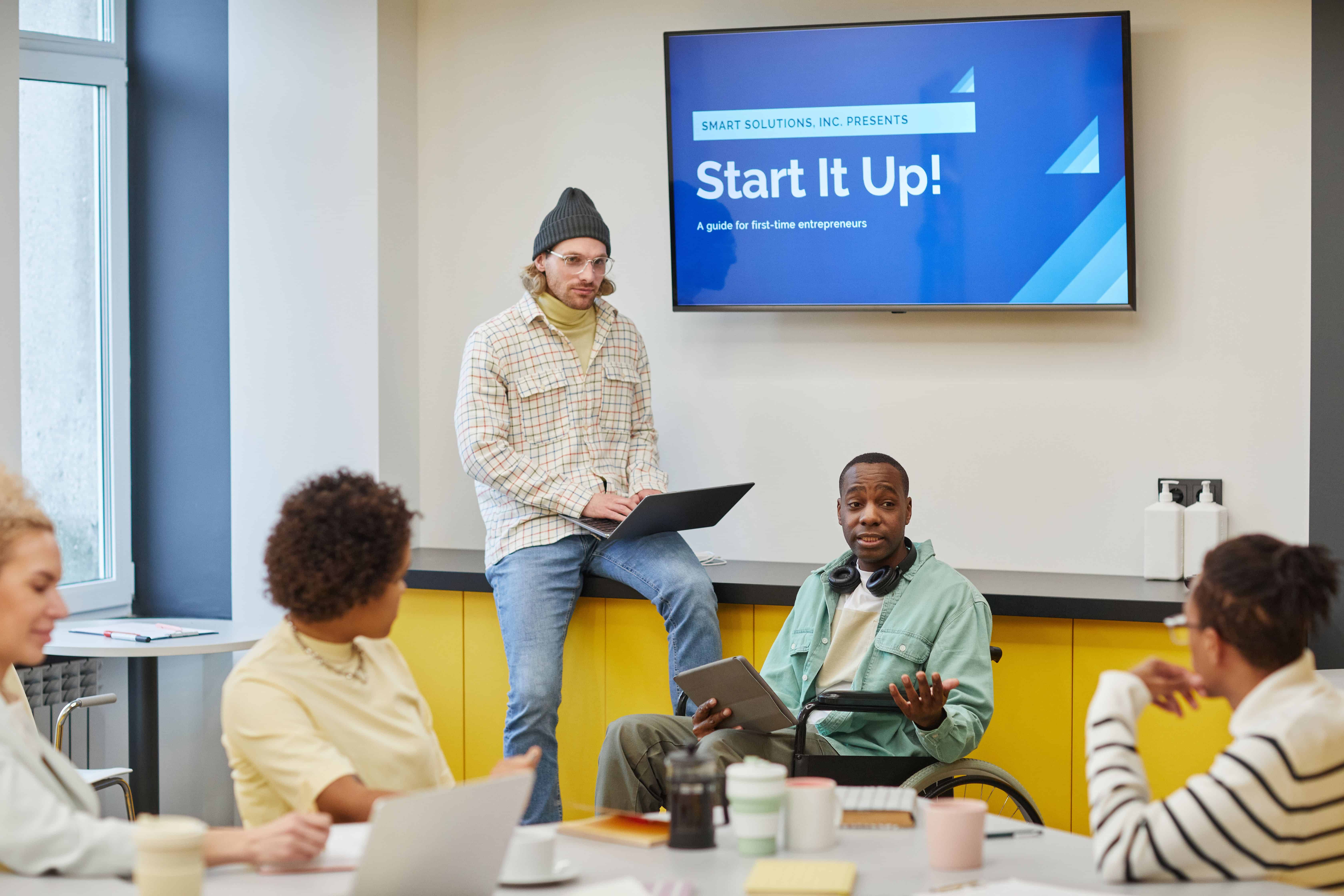 Group meeting with presenter and participants discussing startup guide from screen display.