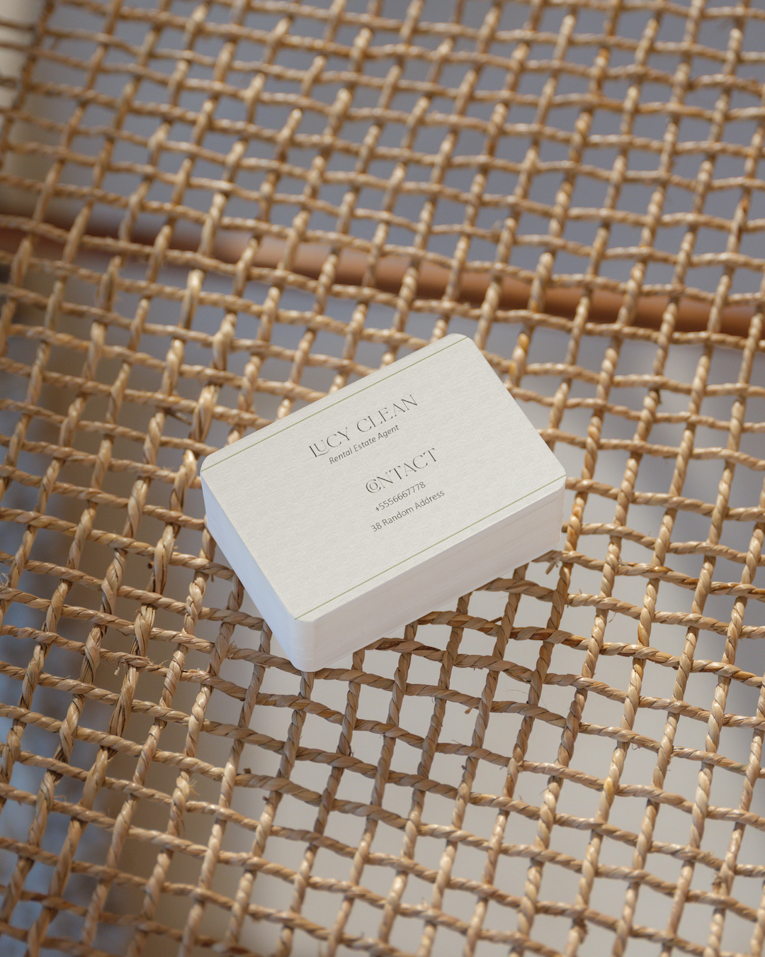 Stack of JUCY CLEAN rental estate agent business cards on woven chair surface.