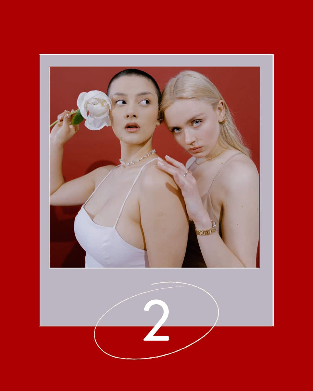 Two women pose against a red background; one holds a white flower and the other rests her hand on her shoulder.