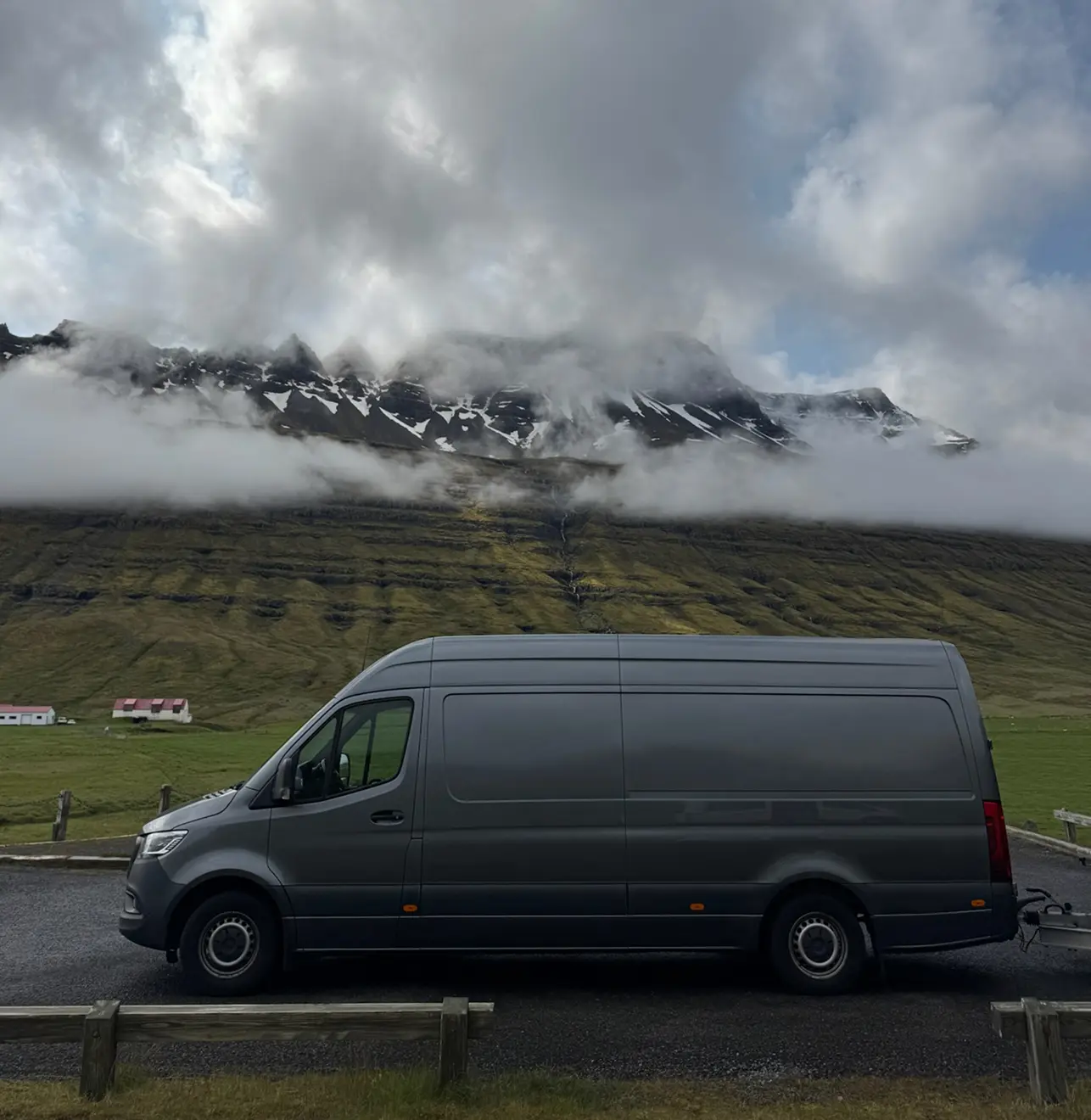 Ein Motorradtransporter Lieferwagen steht vor schneebedeckten Berggipfeln.