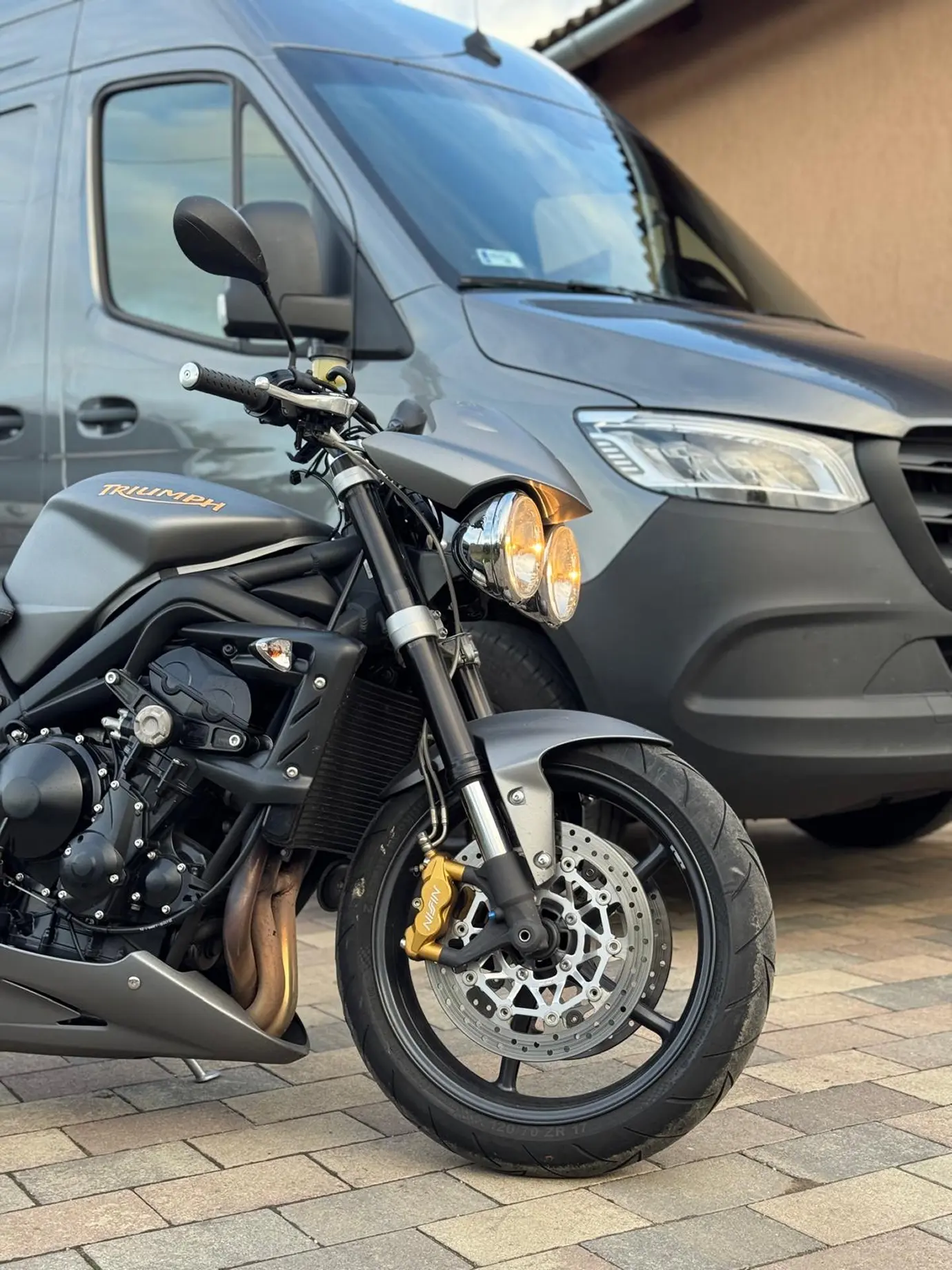 Schwarze Triumph parkt im Hof vor dem Transporter