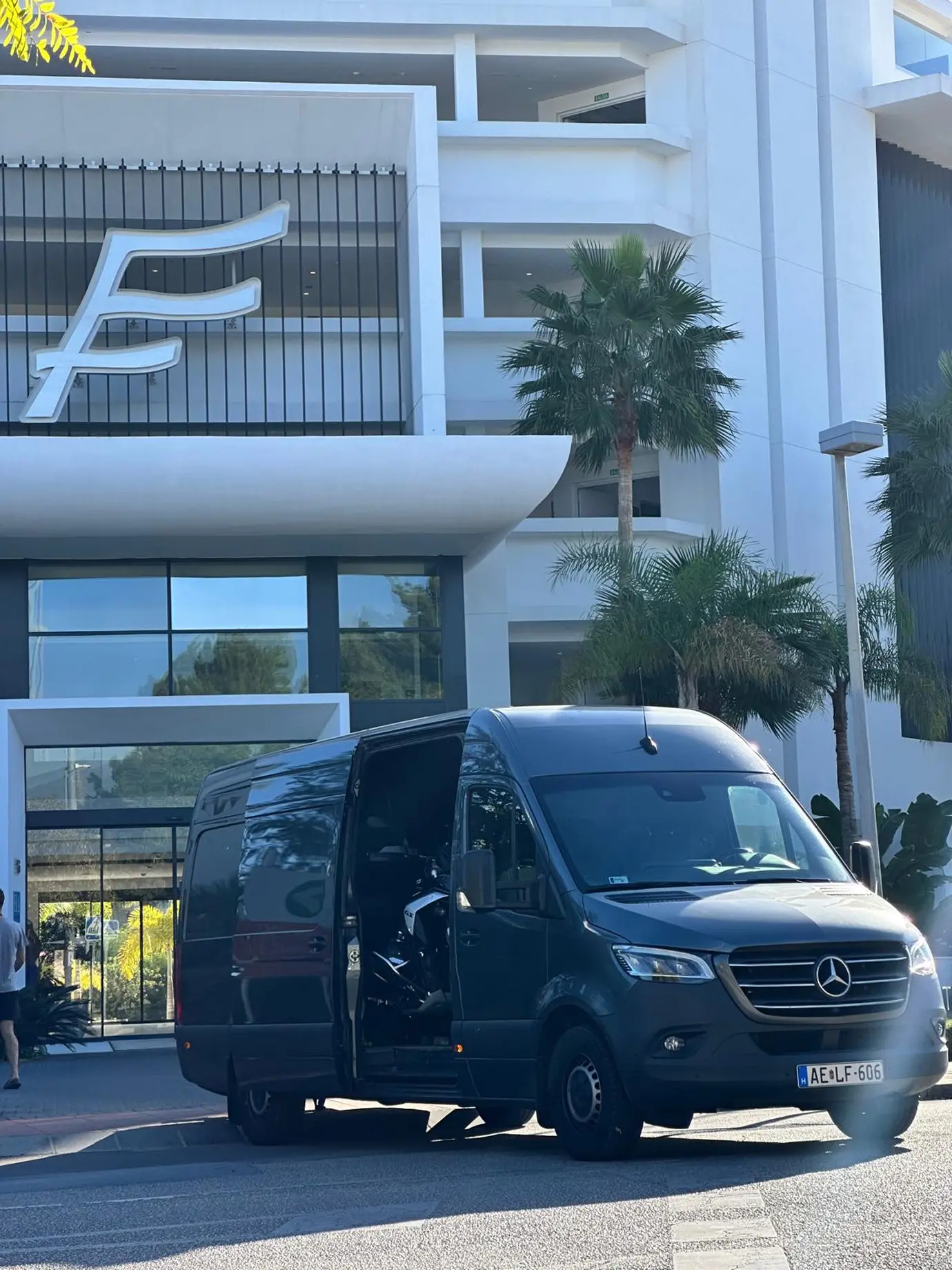 Ein grauer Kleintransporter steht mit offener Tür vor einem Gebäude.