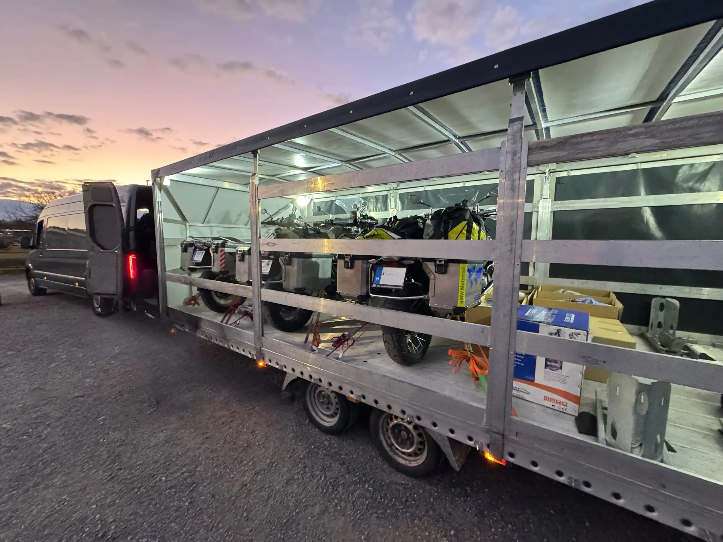 3 Motorräder und Motorradausrüstung sind im geschlossenen Anhänger sicher verzurrt.