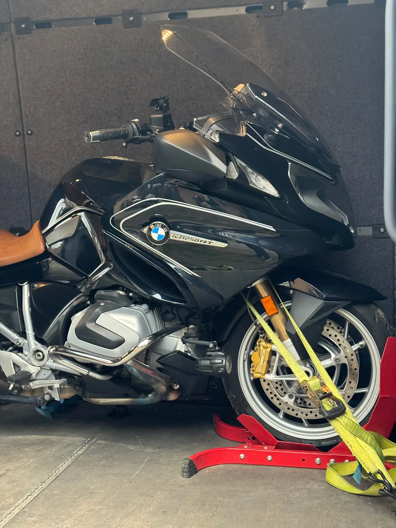 Ein schwarzes Motorrad ist im Kleintransporter sicher verzurrt.