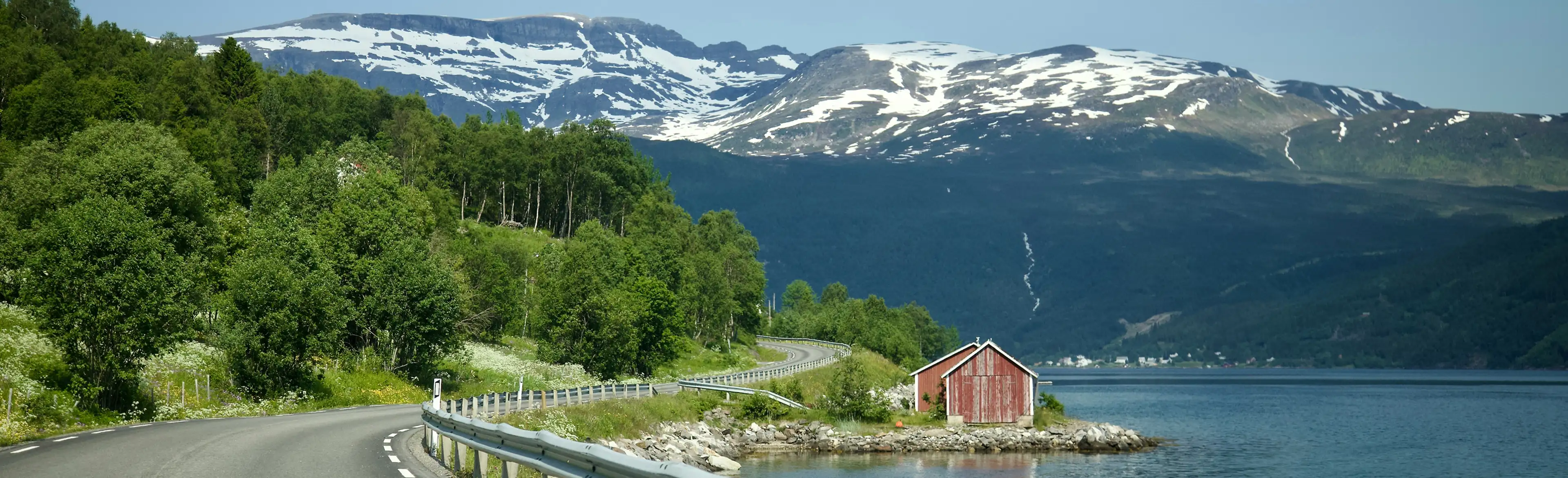 Asphaltwege entlang der Fjorde, im Hintergrund schneebedeckte Berge.