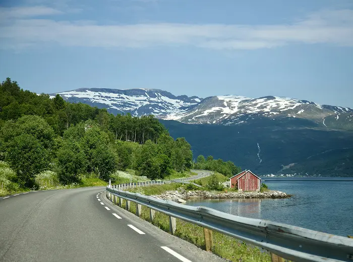 Asphaltwege entlang der Fjorde, im Hintergrund schneebedeckte Berge.
