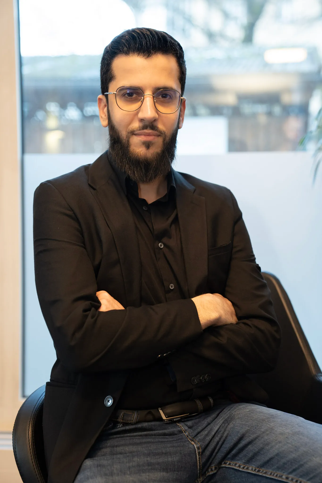 Vier junge Erwachsene arbeiten an einem Tisch in einem modernen Büro mit Stadtblick.