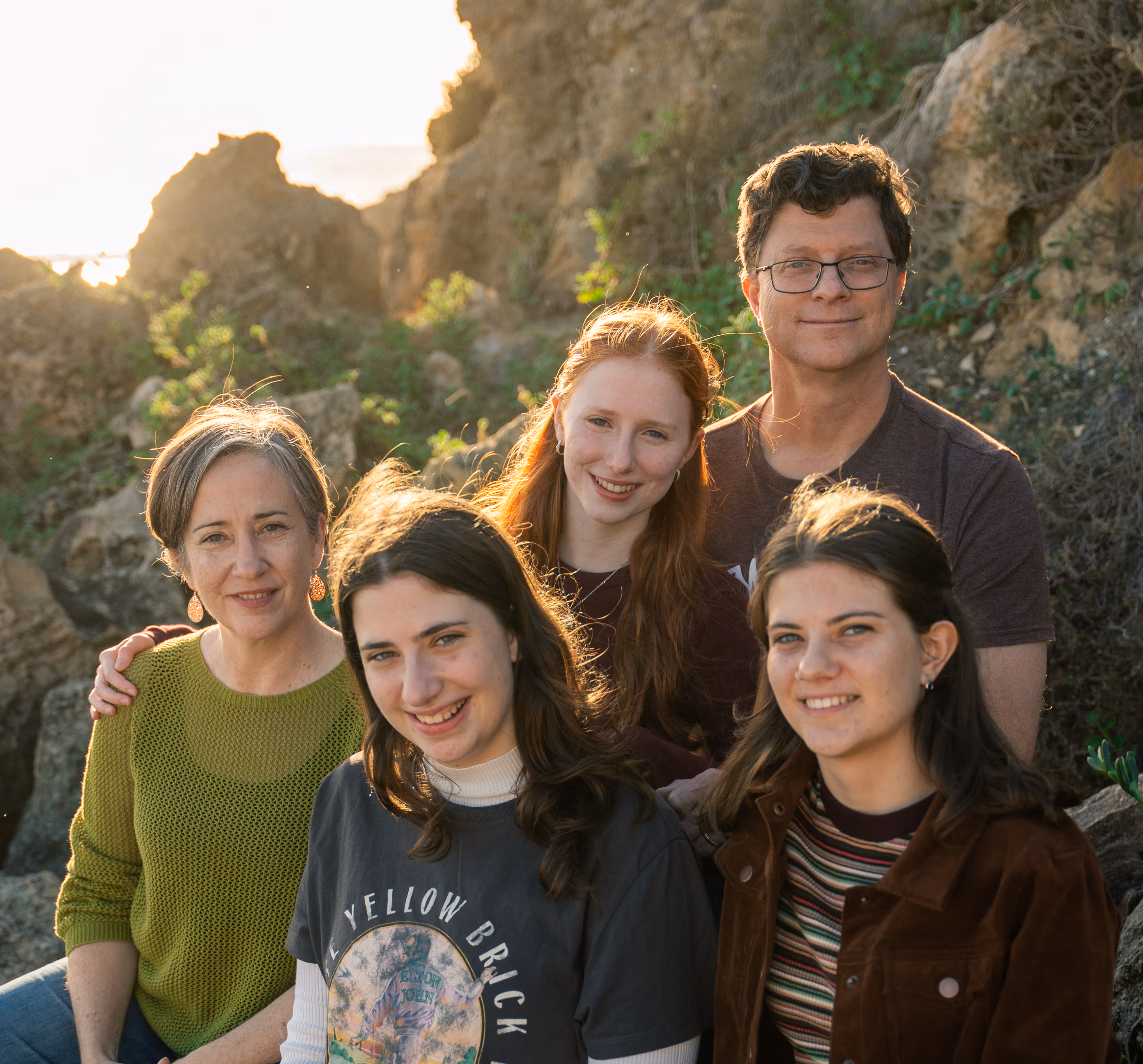Family laughing and sitting together on the cliffs by the sea