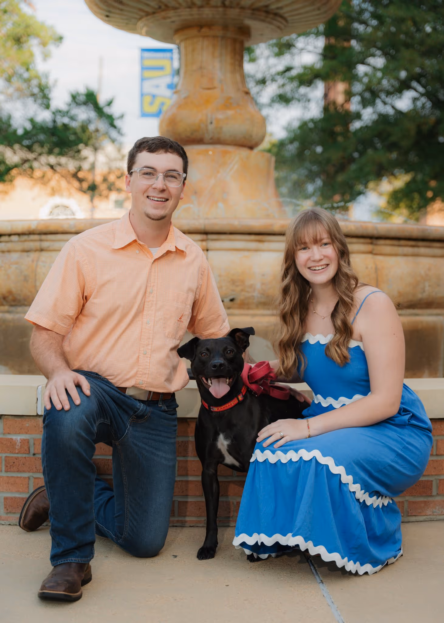Couple's portrait with a dog in front of a fountain