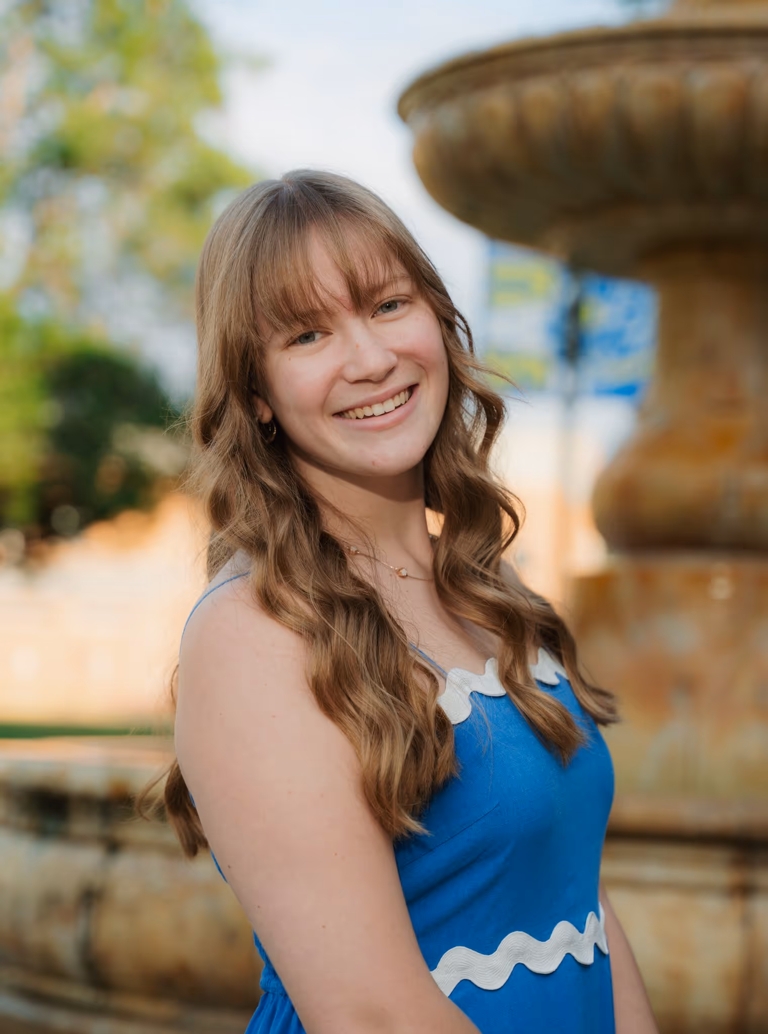 Portrait of a young woman in front of a fountain