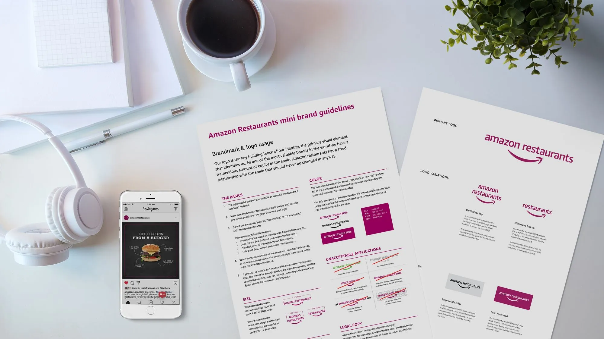 Desktop workspace with Amazon Restaurants brand guidelines documents, coffee cup, and phone displaying burger infographic on Instagram.