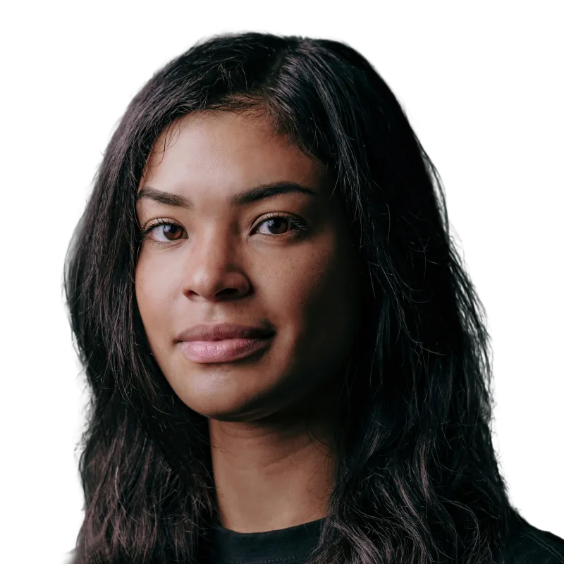 Portrait of a woman with long dark hair and neutral expression against a black background.