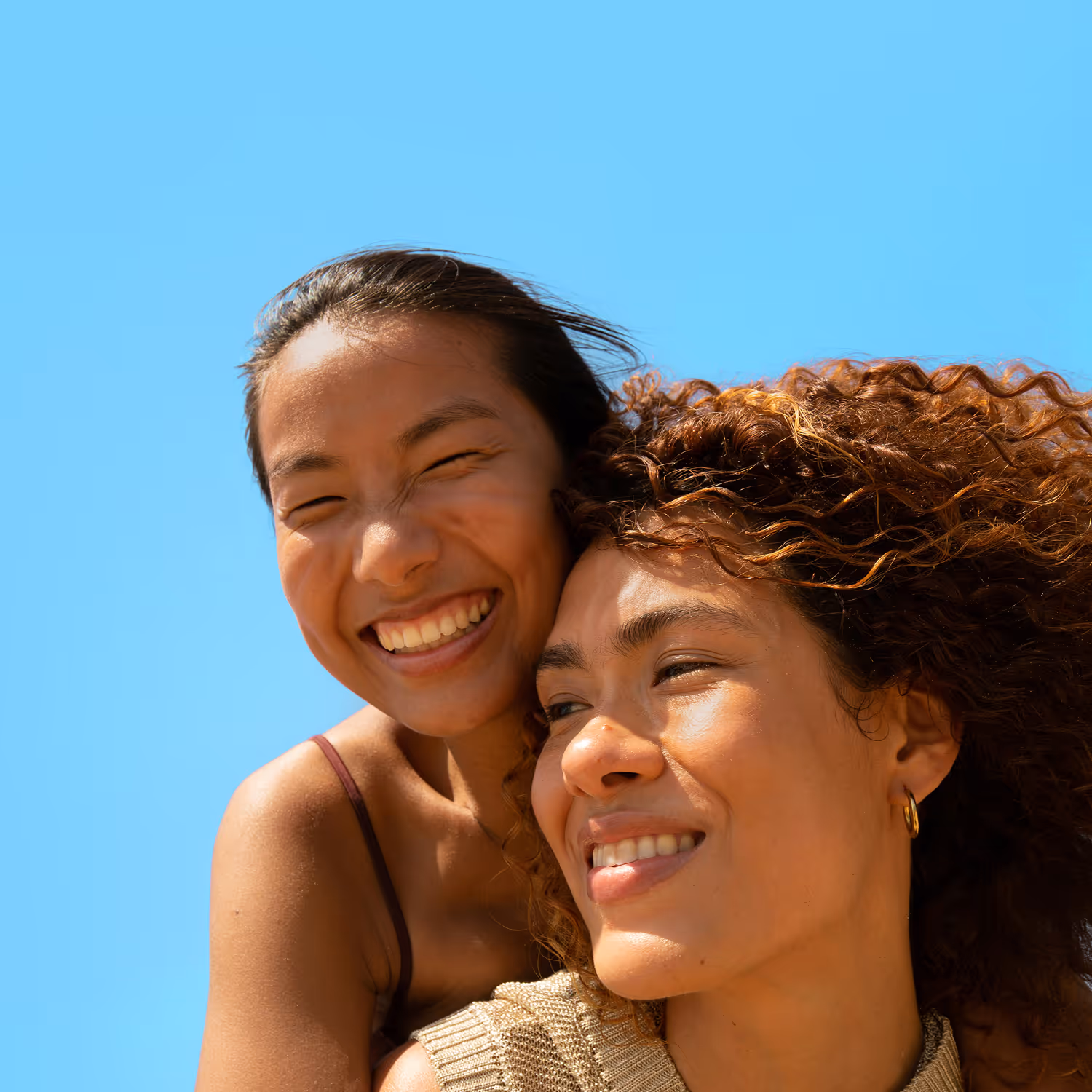 Woman with short curly hair wearing a coral t-shirt looking over a cityscape from a hilltop at dusk.