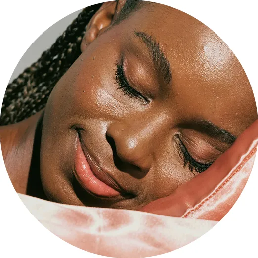 Close-up of a woman peacefully sleeping with head resting on a pink satin pillow.