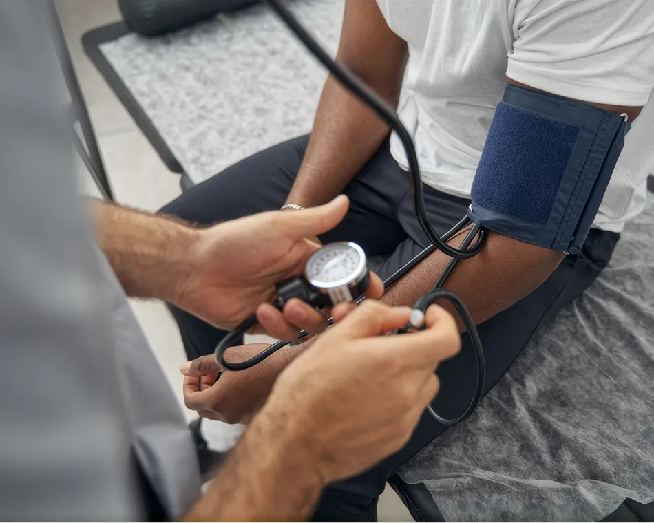 Healthcare professional measuring blood pressure on a seated man's arm with a cuff.