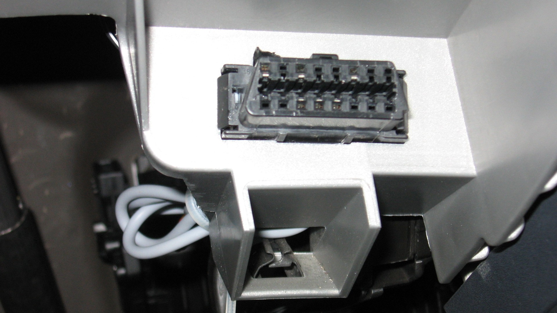 Close-up of a standard 16-pin OBD-II port under a vehicle dashboard