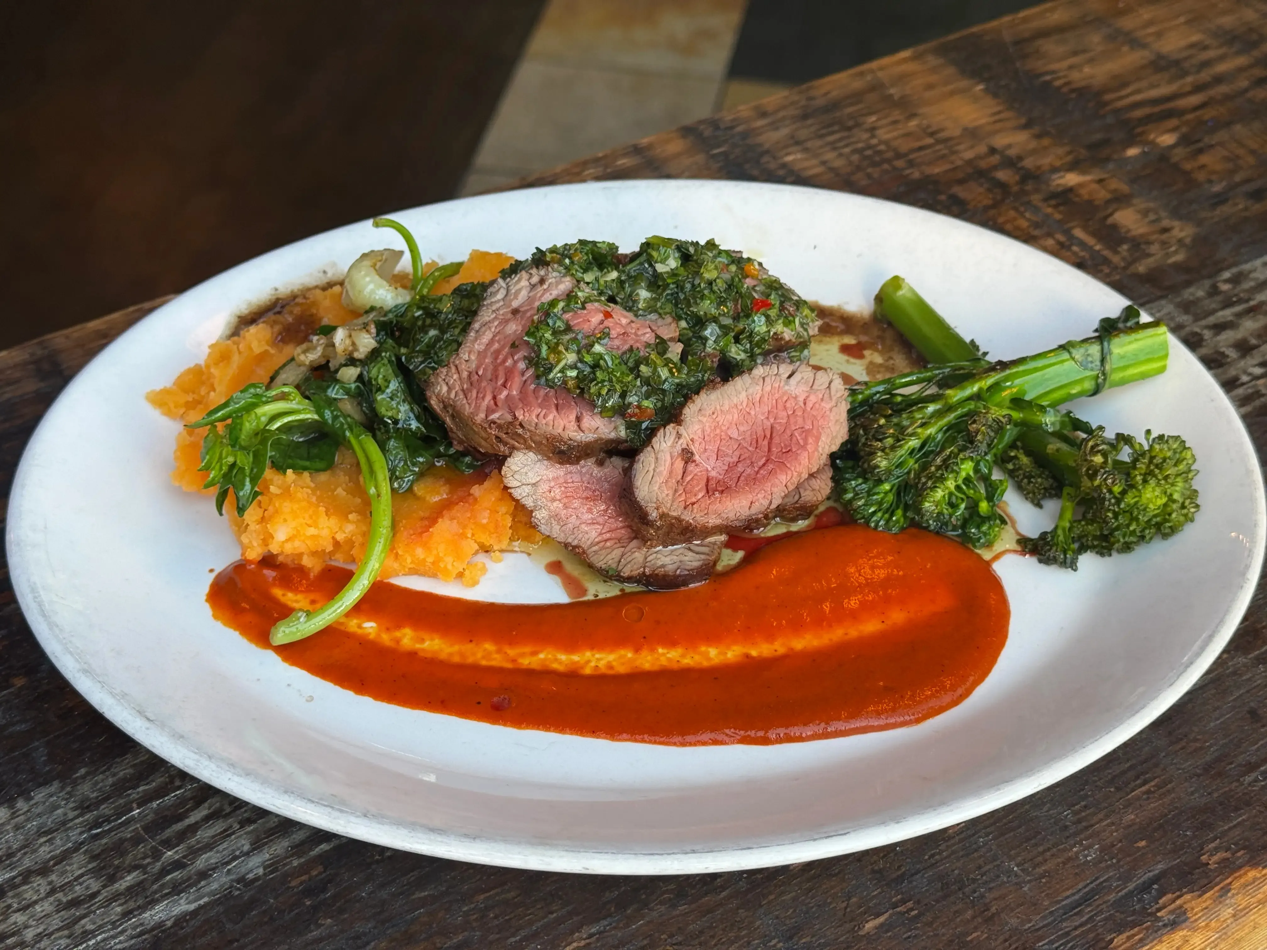 A plate of food featuring various ingredients, including venison and vegetables, arranged artfully on a dining table.