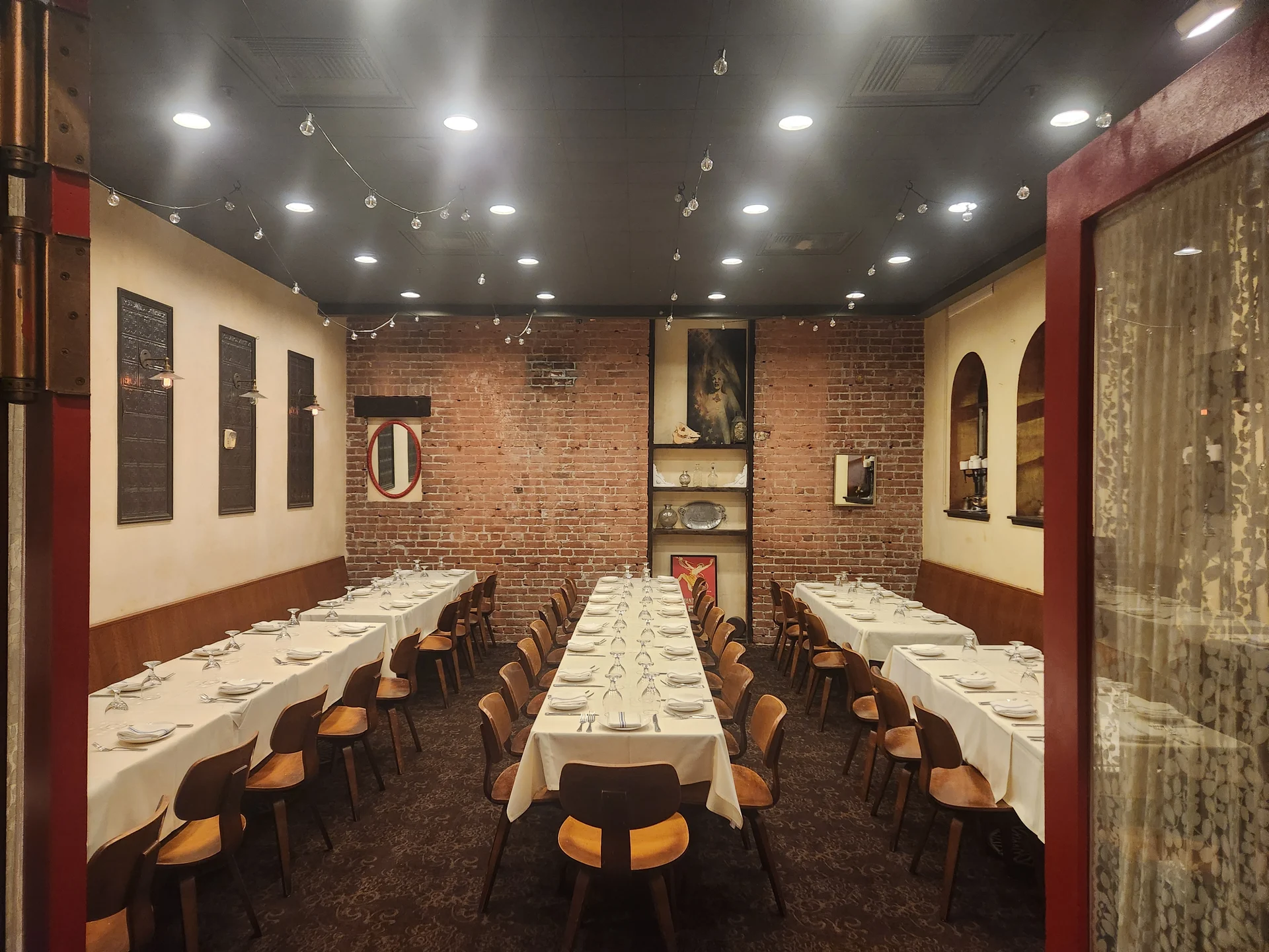 A restaurant with a brick wall and a long table with chairs.